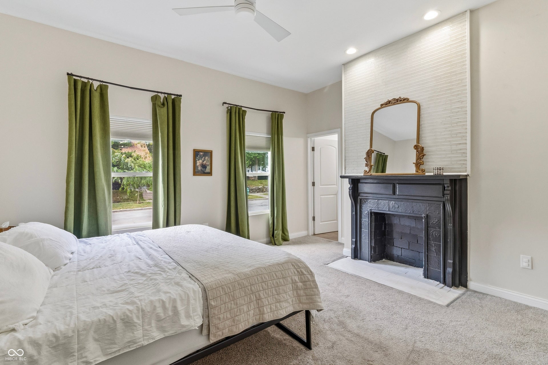 Primary bedroom with vaulted ceilings, neutral colors, decorative fireplace, and en suite full bathroom.