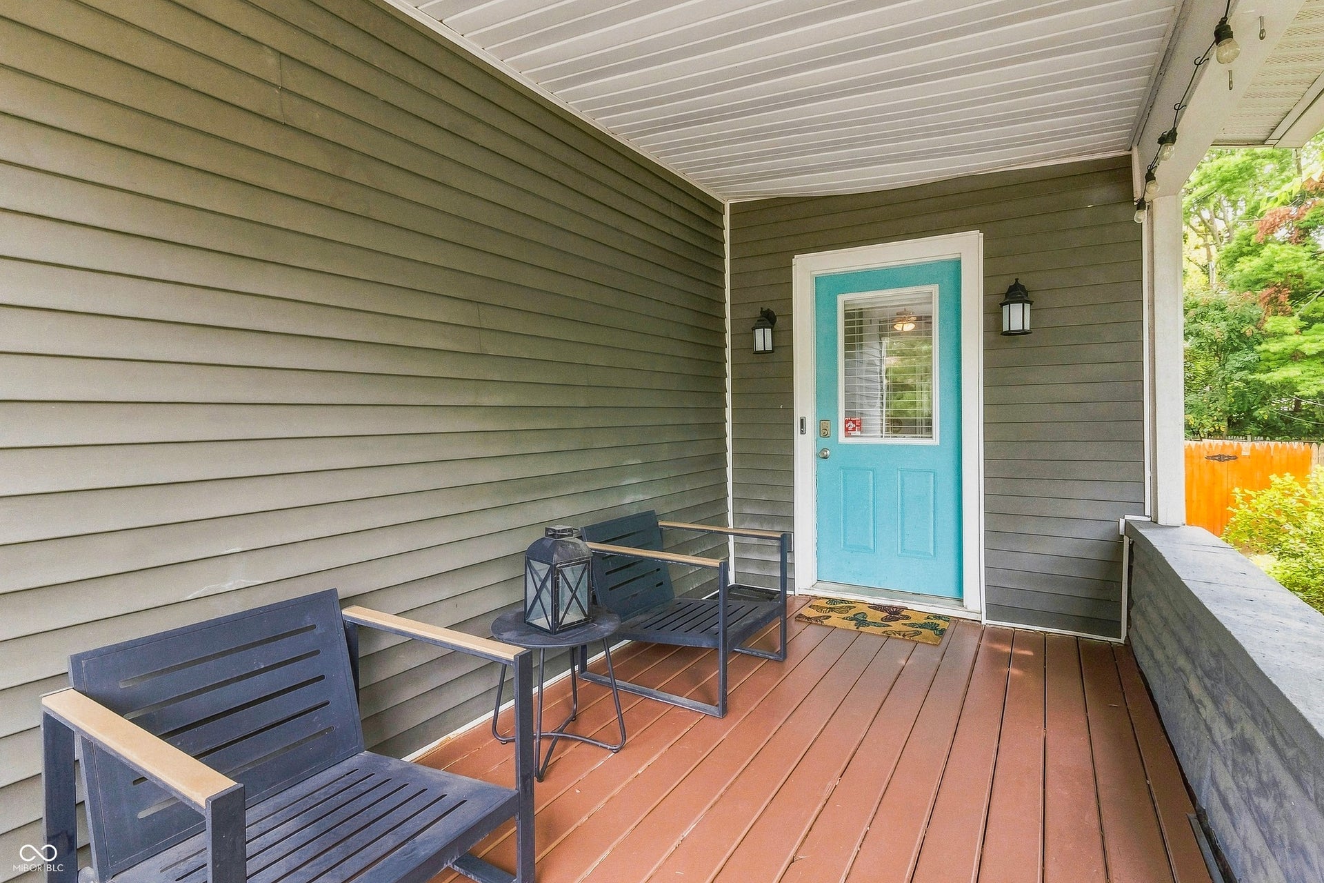 Quaint covered front porch area featuring wood-finish decking and plenty of room for relaxing outdoors