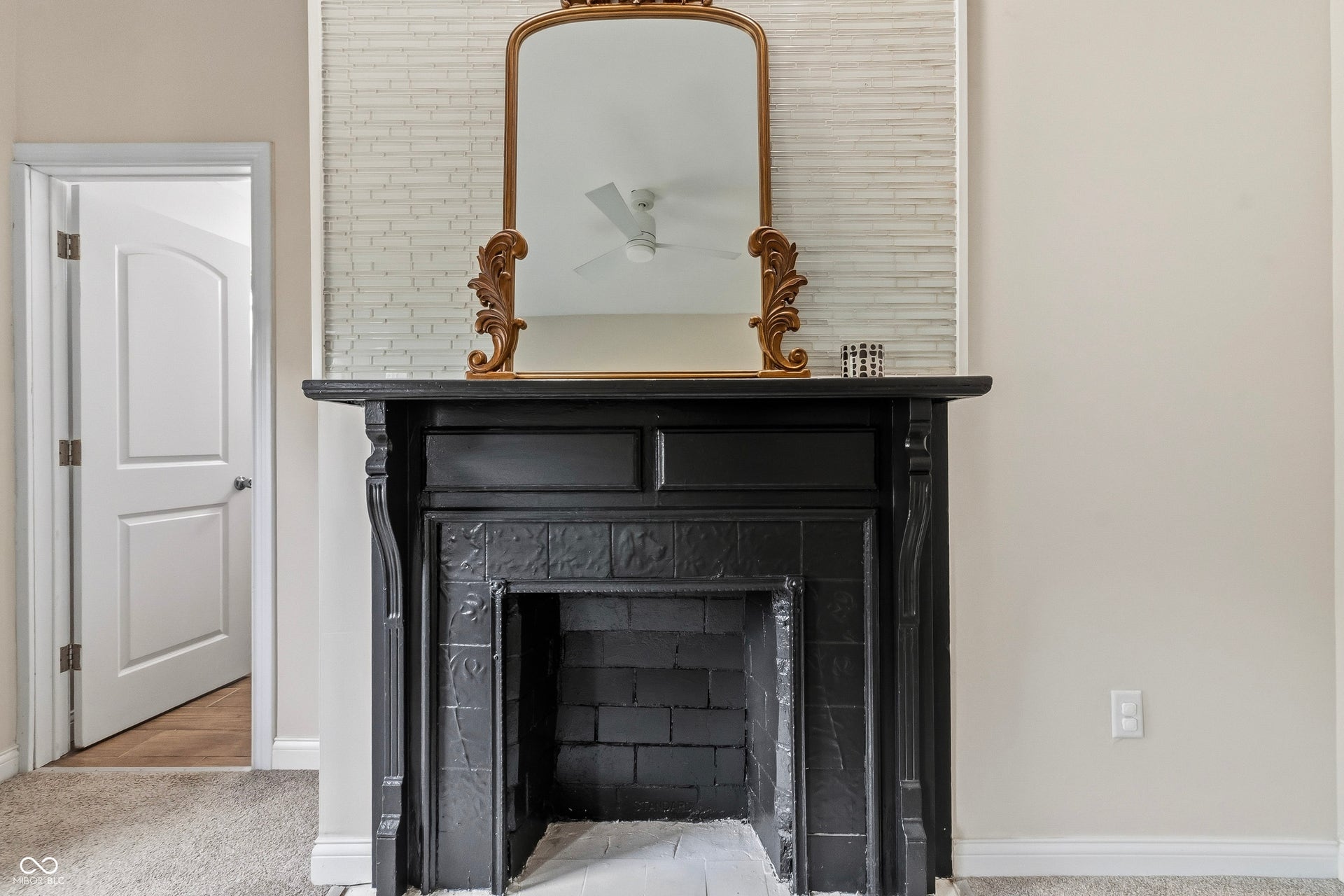 Black decorative fireplace with tile surround, recessed lighting, and carved wood mantel