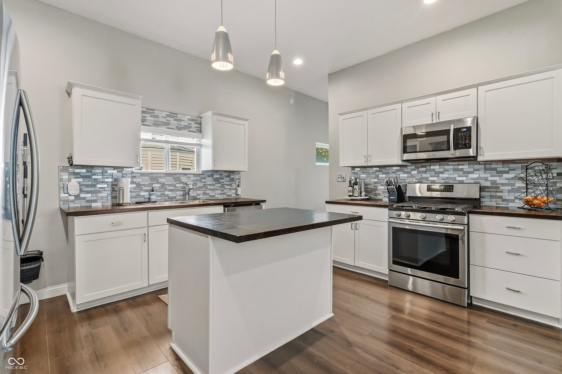 Kitchen featuring a central island, butcher block counter tops, decorative back splash, and stainless steel appliances