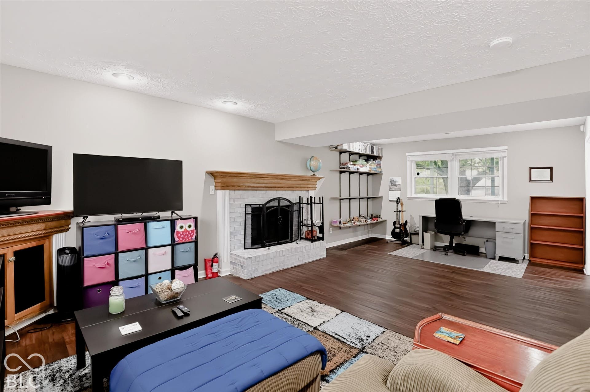 Living space featuring a brick fireplace with a wood mantel, wood-finish flooring, and recessed lighting