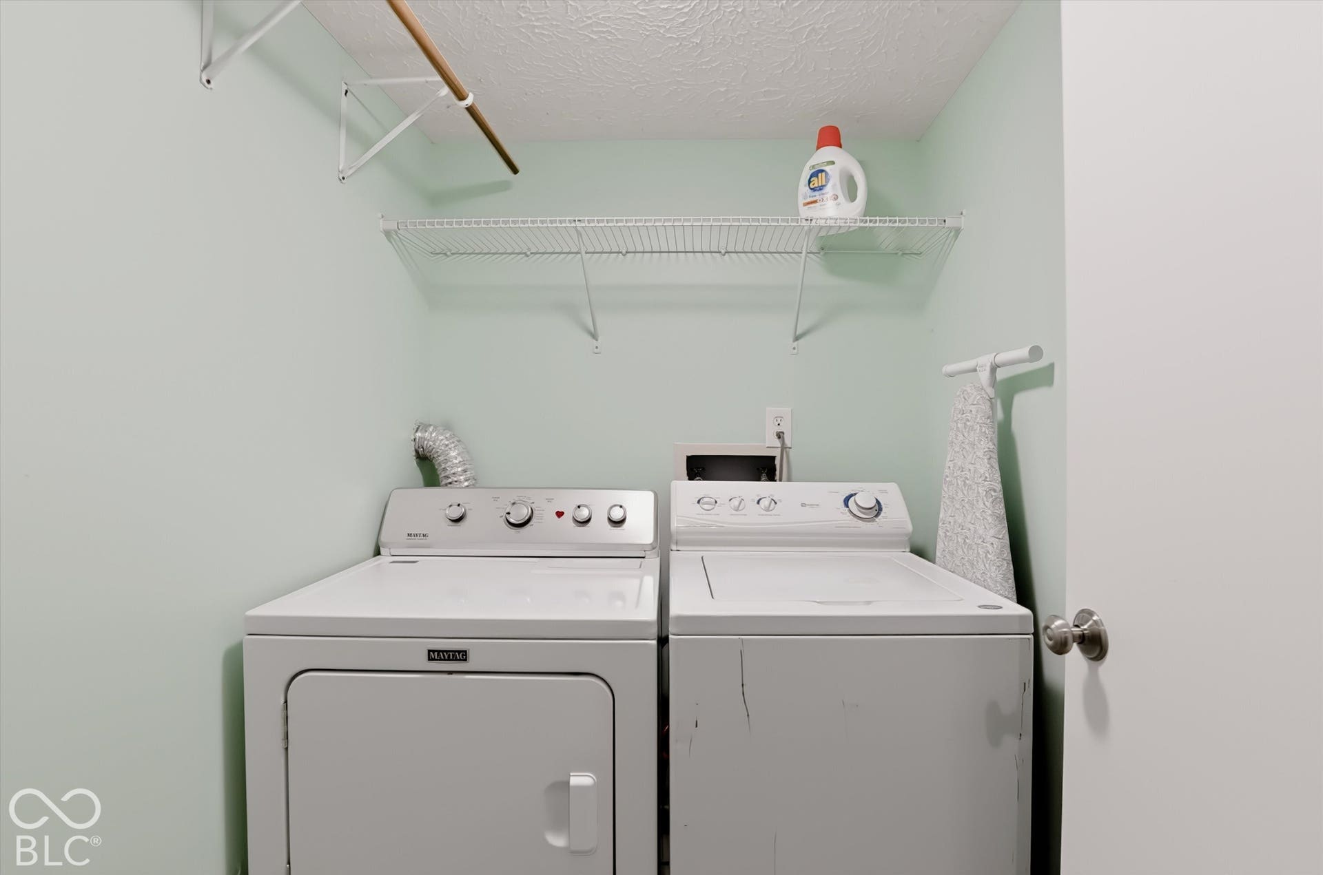 Laundry area featuring dual wire shelving and a mounted garment rod