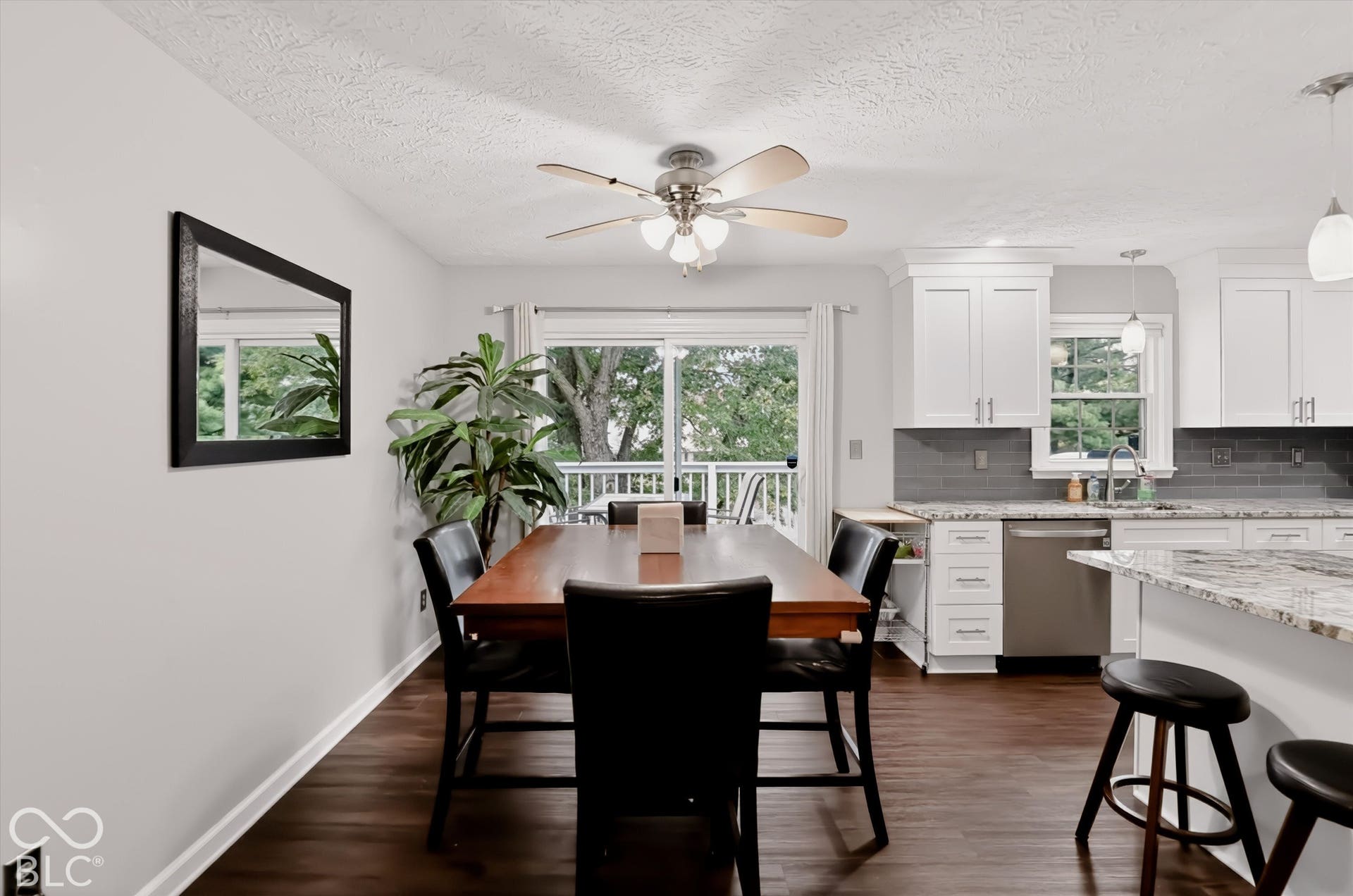 Kitchen featuring wood-finish flooring, white cabinetry, stone-finish countertops, subway tile backsplash, and a sliding glass door