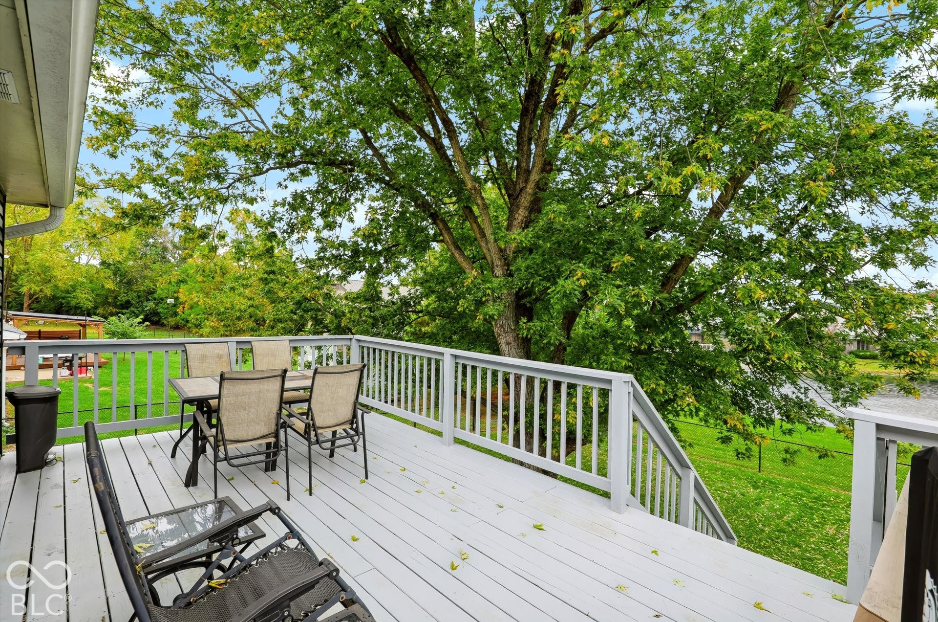 Raised deck featuring light-toned painted wood planks, a perimeter balustrade, and a staircase leading to the yard