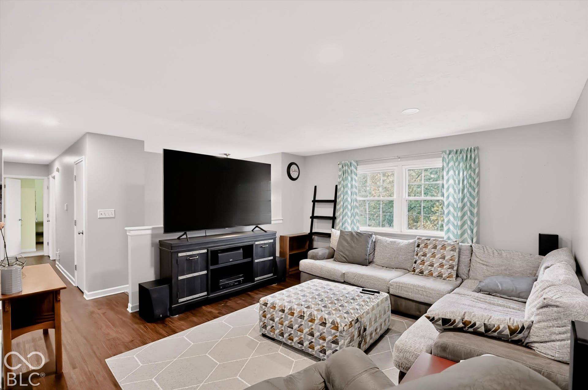 Open-concept living space featuring wood-finish flooring, neutral wall paint, and a pony wall divider with a cap rail