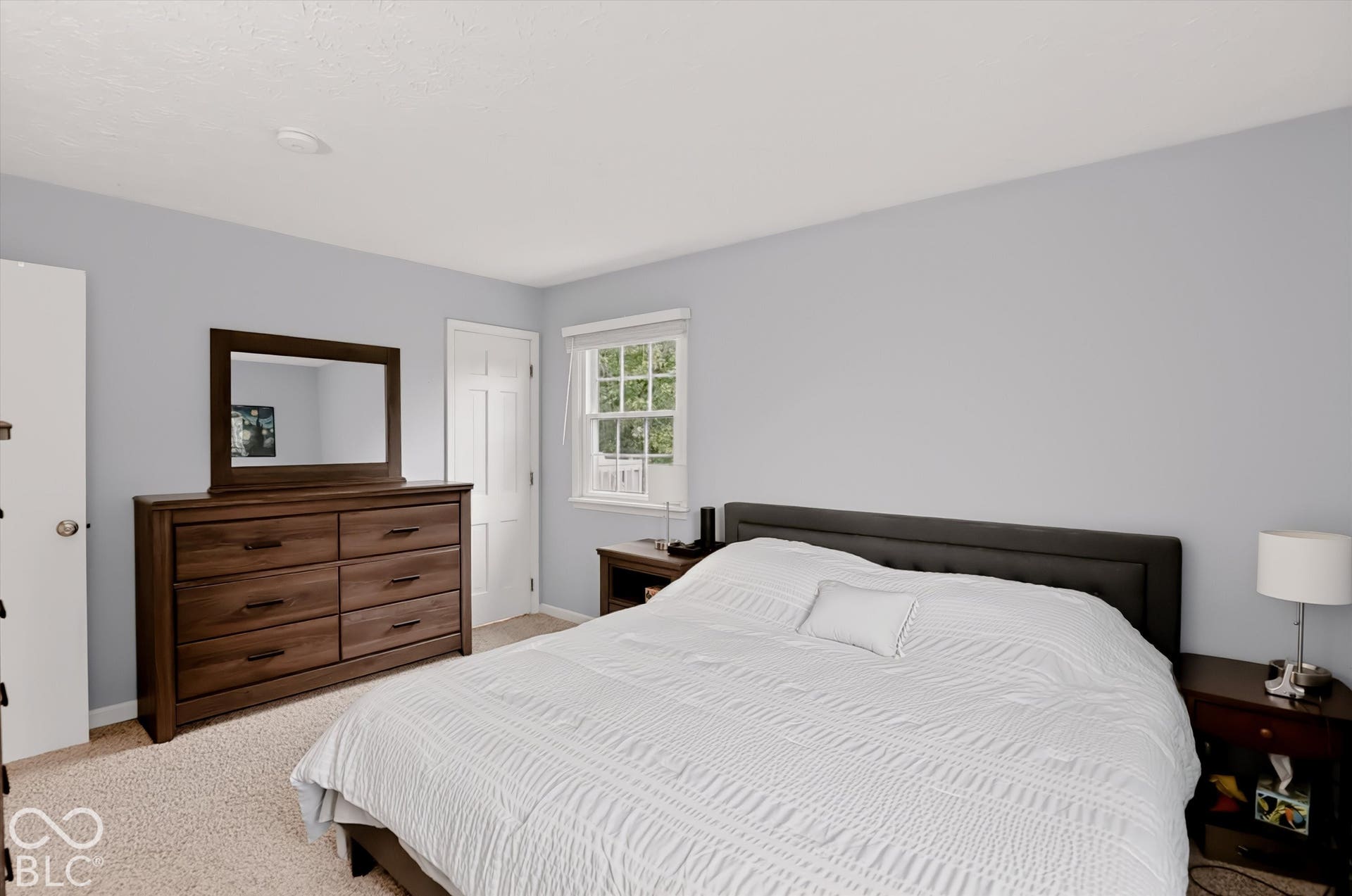 Neutral wall tones, wall-to-wall carpeting, single-hung window with a classic grid pattern, and interior doors with a six-panel design