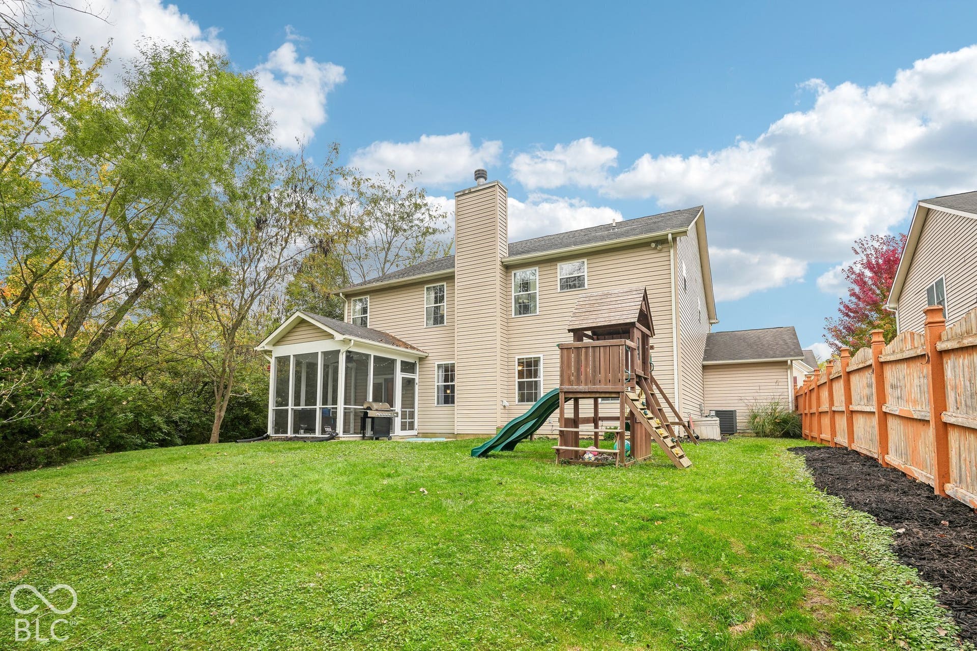 Private backyard offers views of the woods with covered porch, open patio, playset, and tons of space to enjoy