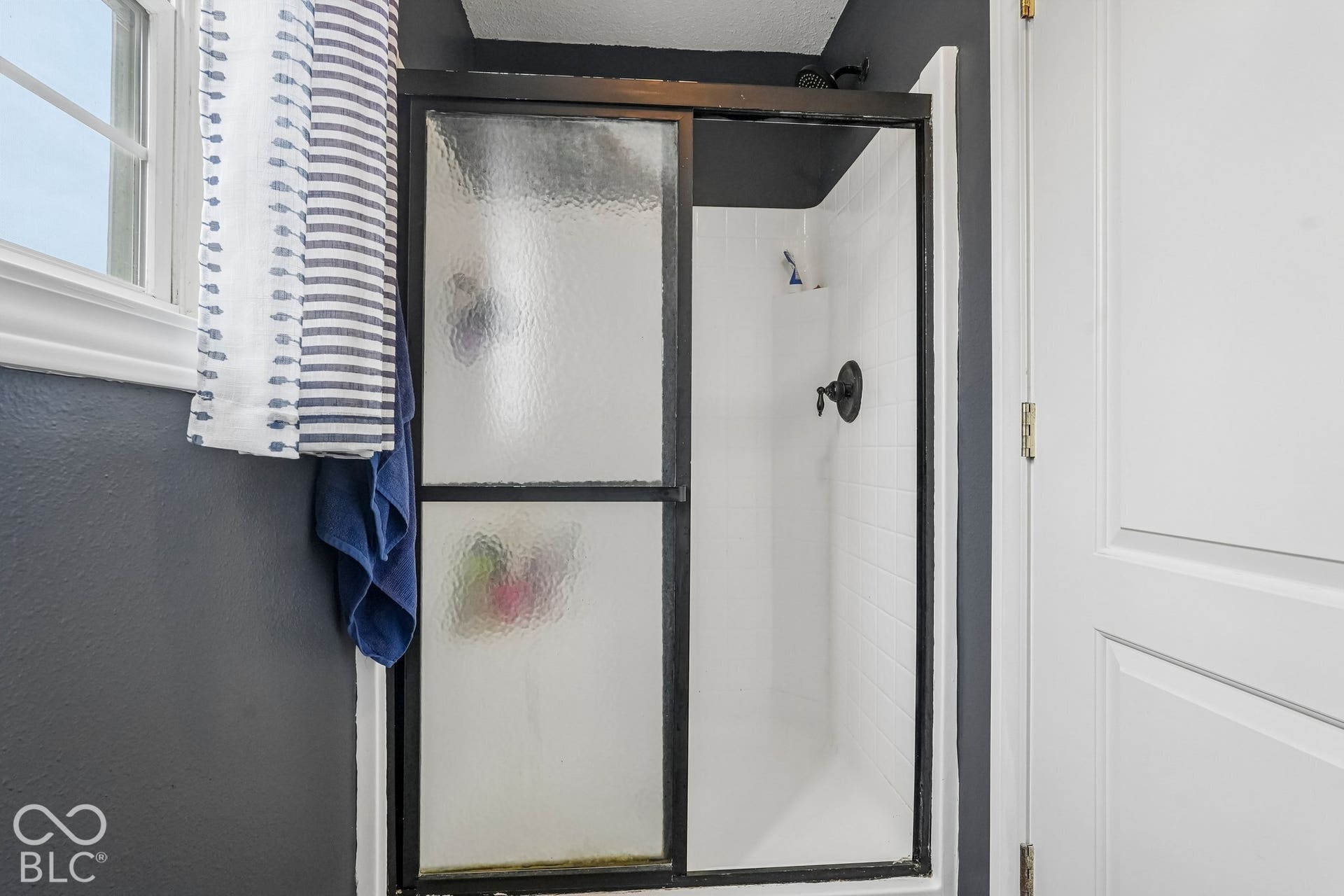 Full shower with black glass framed doors located in the private water closet area of the primary bathroom