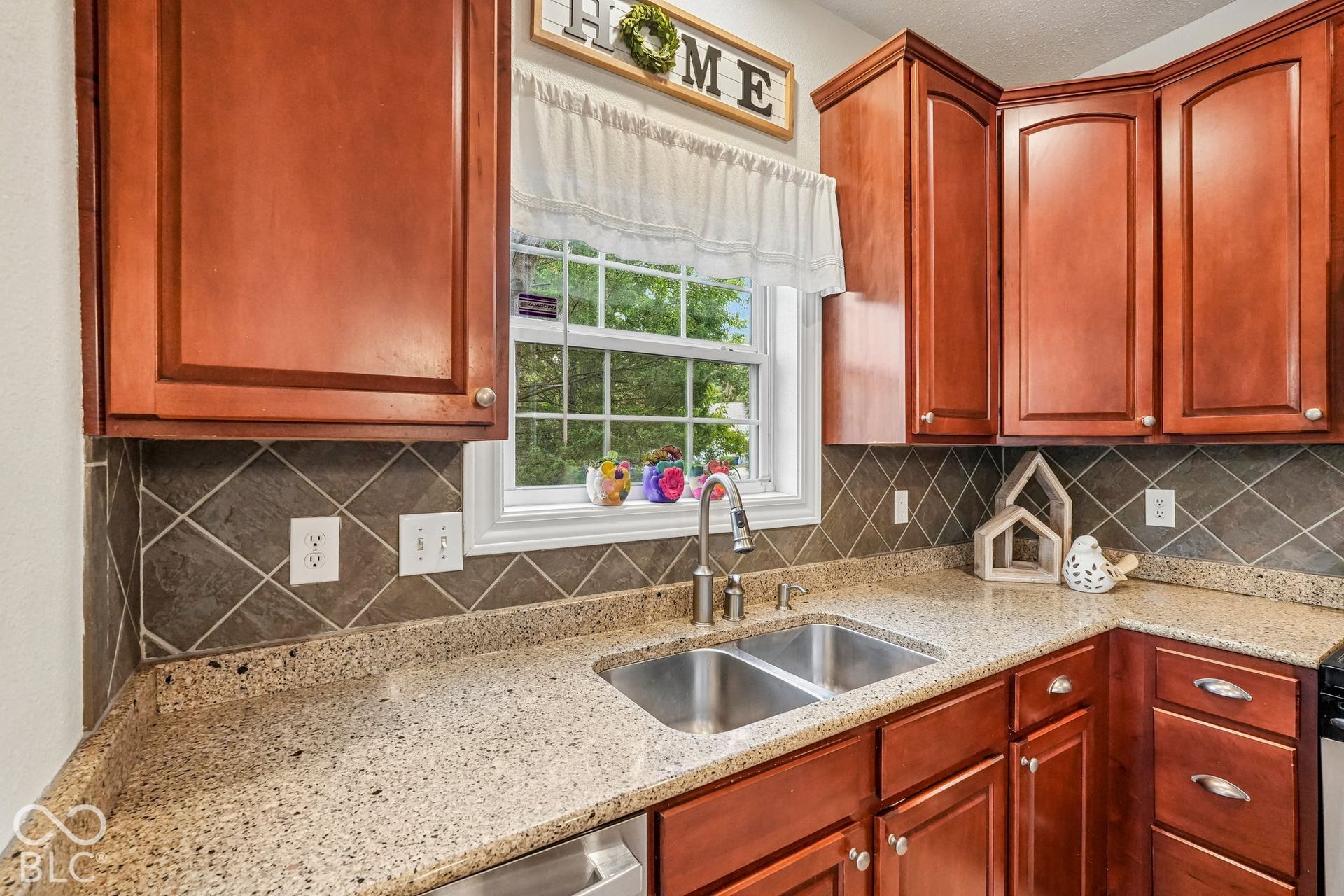 Kitchen offers tiled backsplash and window overlooking the wooded area with no neighbors on this side