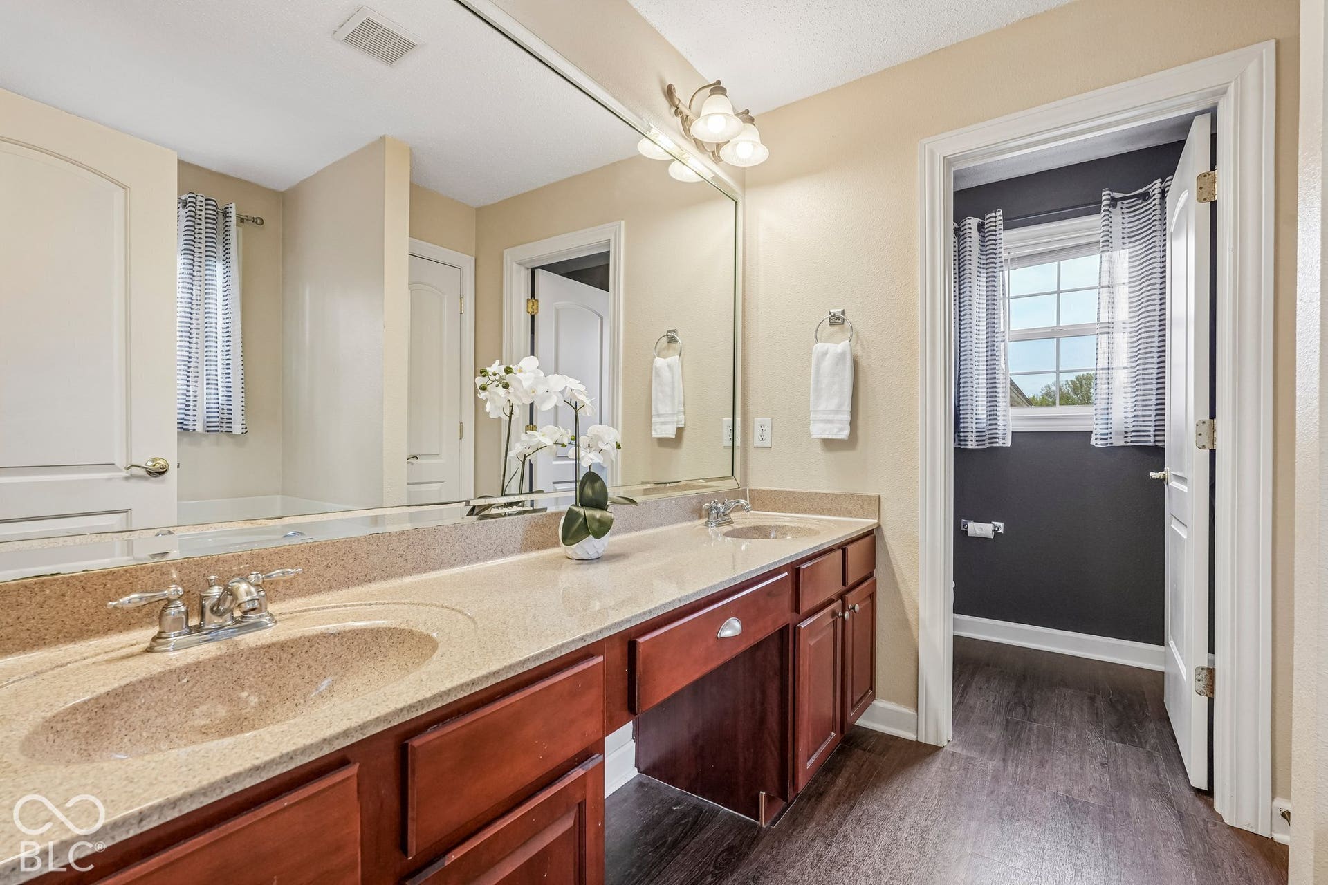 Ensuite primary bathroom offers double sinks, linen closet, deep jetted tub, and separate water closet with shower
