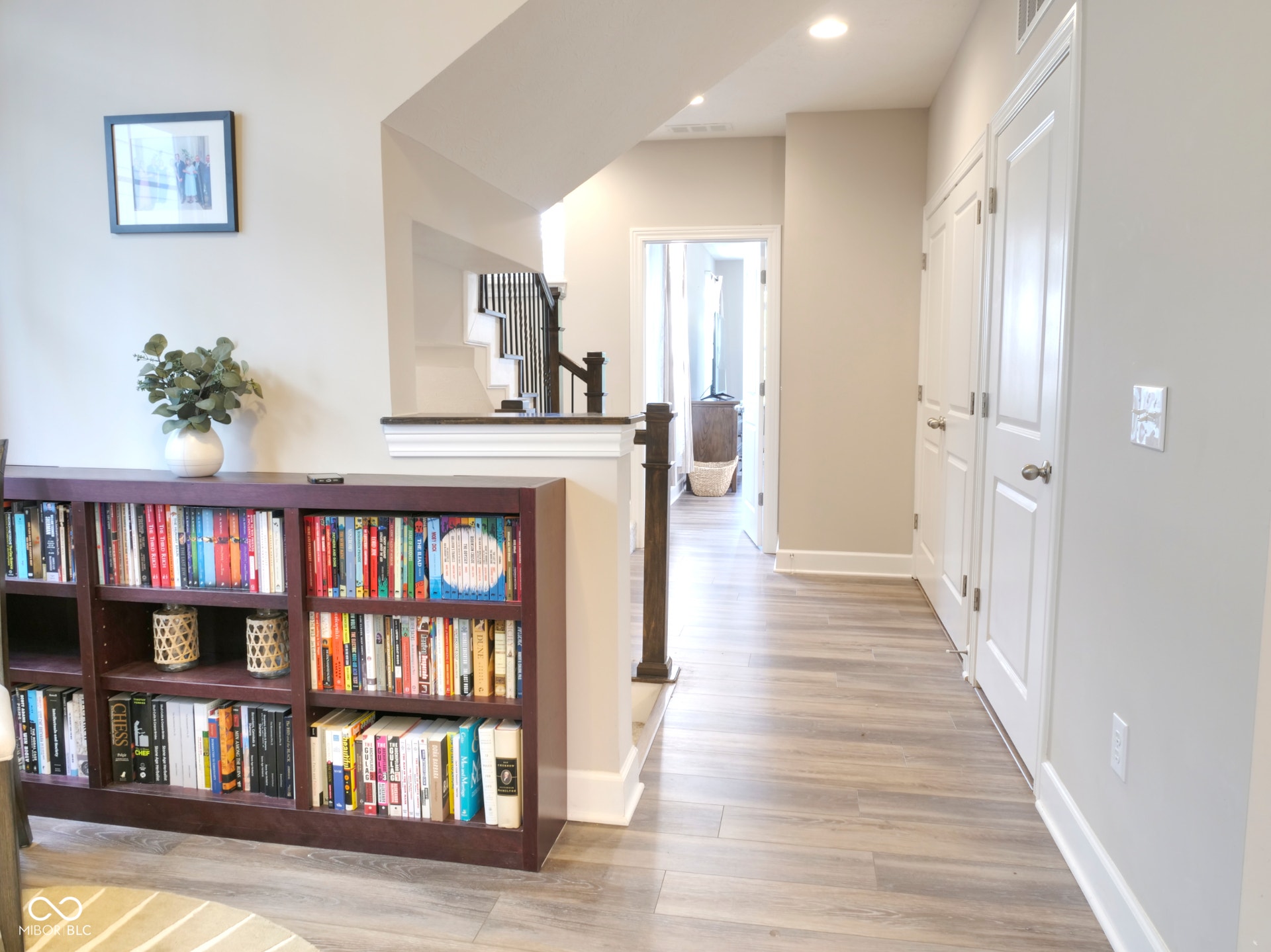 Wood-finish flooring, recessed lighting, white interior doors, and a staircase with dark wood handrails