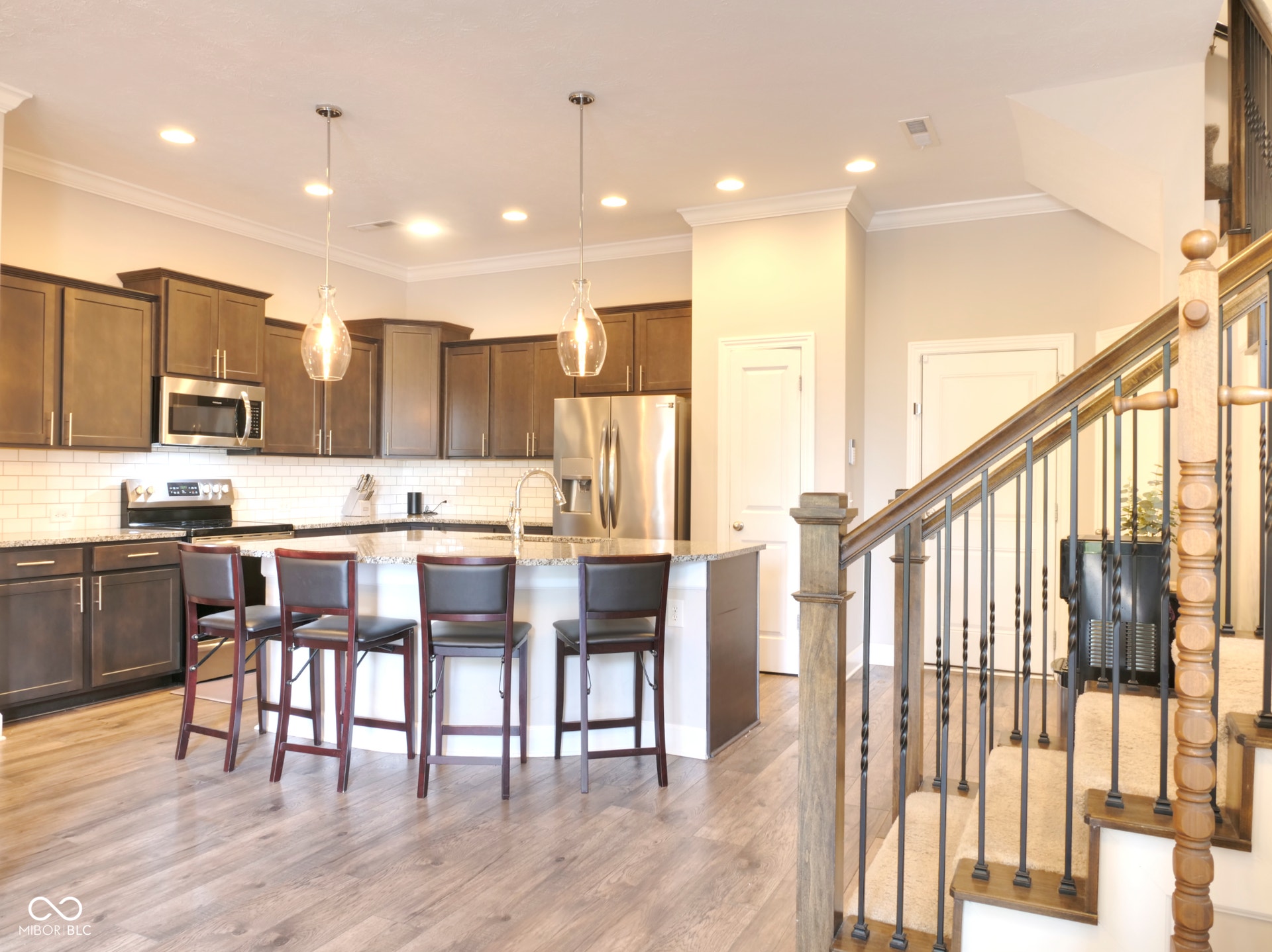 Kitchen featuring wood-finish flooring, dark wood cabinetry, a white subway tile backsplash, and an island with seating