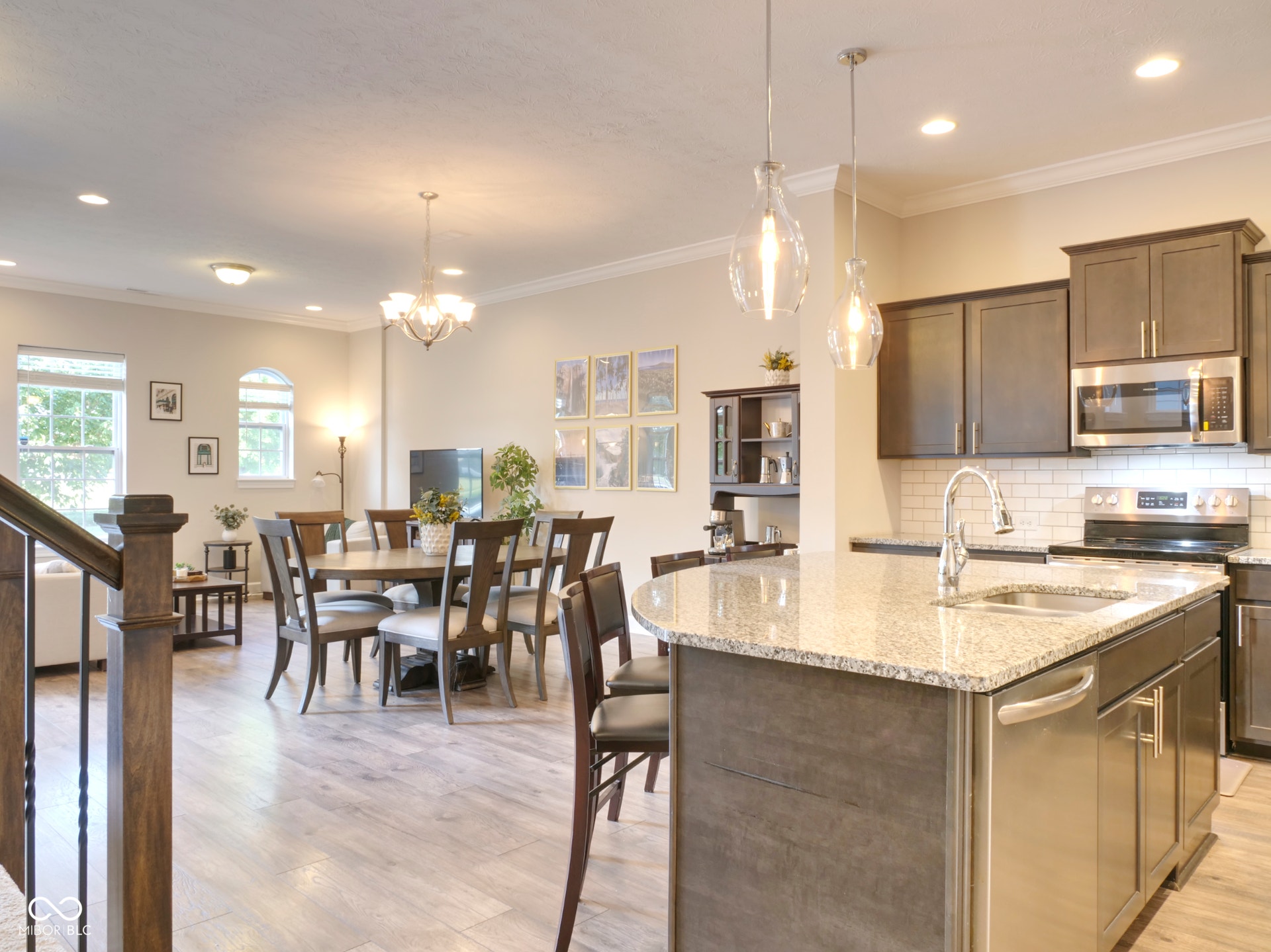 Kitchen island with granite countertop, stainless steel appliances, subway tile backsplash, wood-finish flooring, and recessed lighting