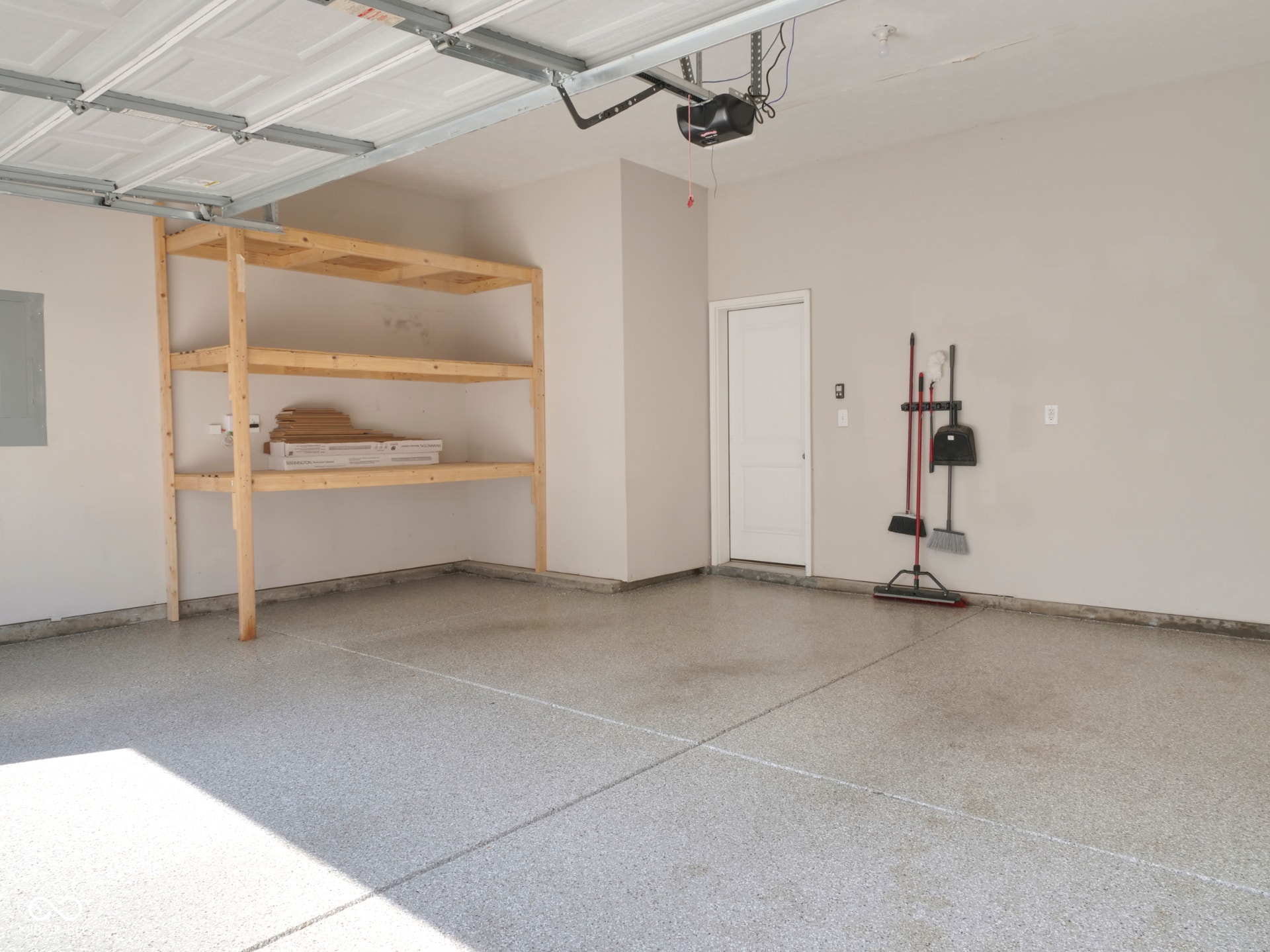 Garage with epoxy flooring, built-in shelving, and a paneled door