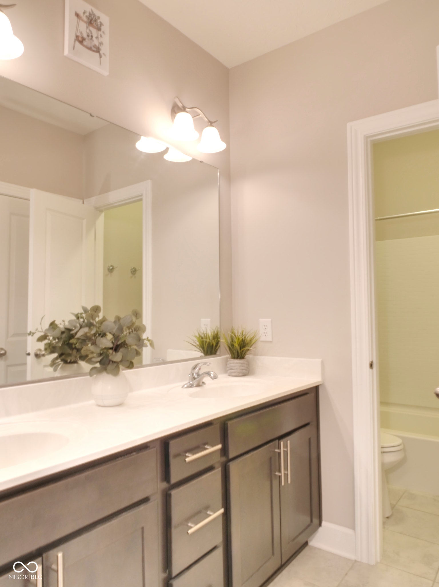 Dual vanity with a white countertop, brushed nickel fixtures, and dark wood-finish cabinetry
