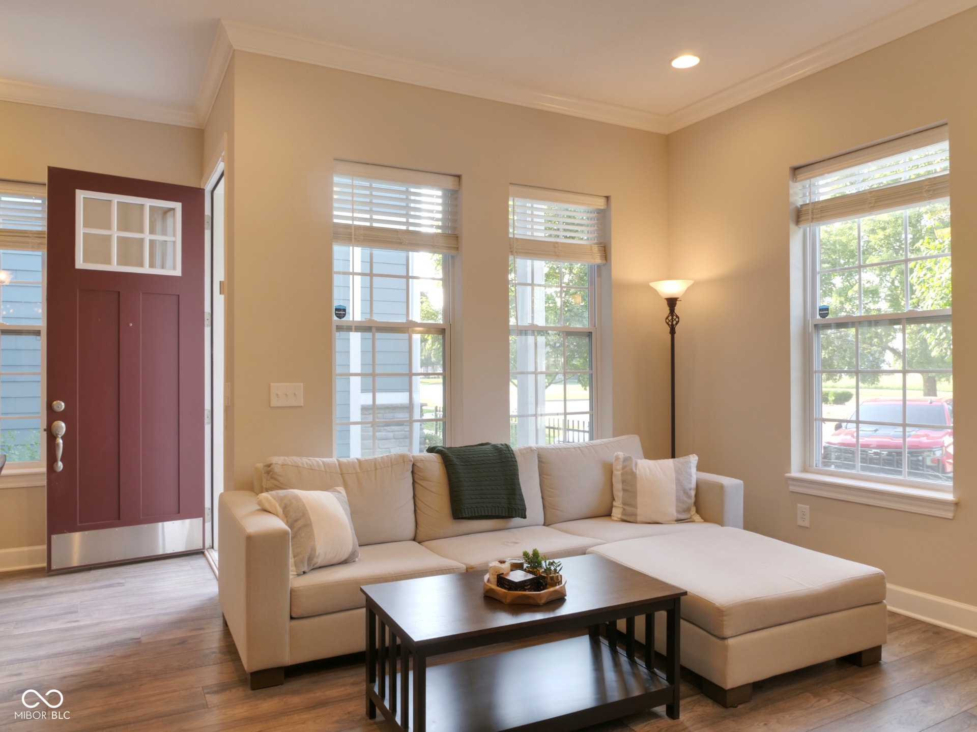 Warm wood-finish flooring, recessed lighting, and crown molding