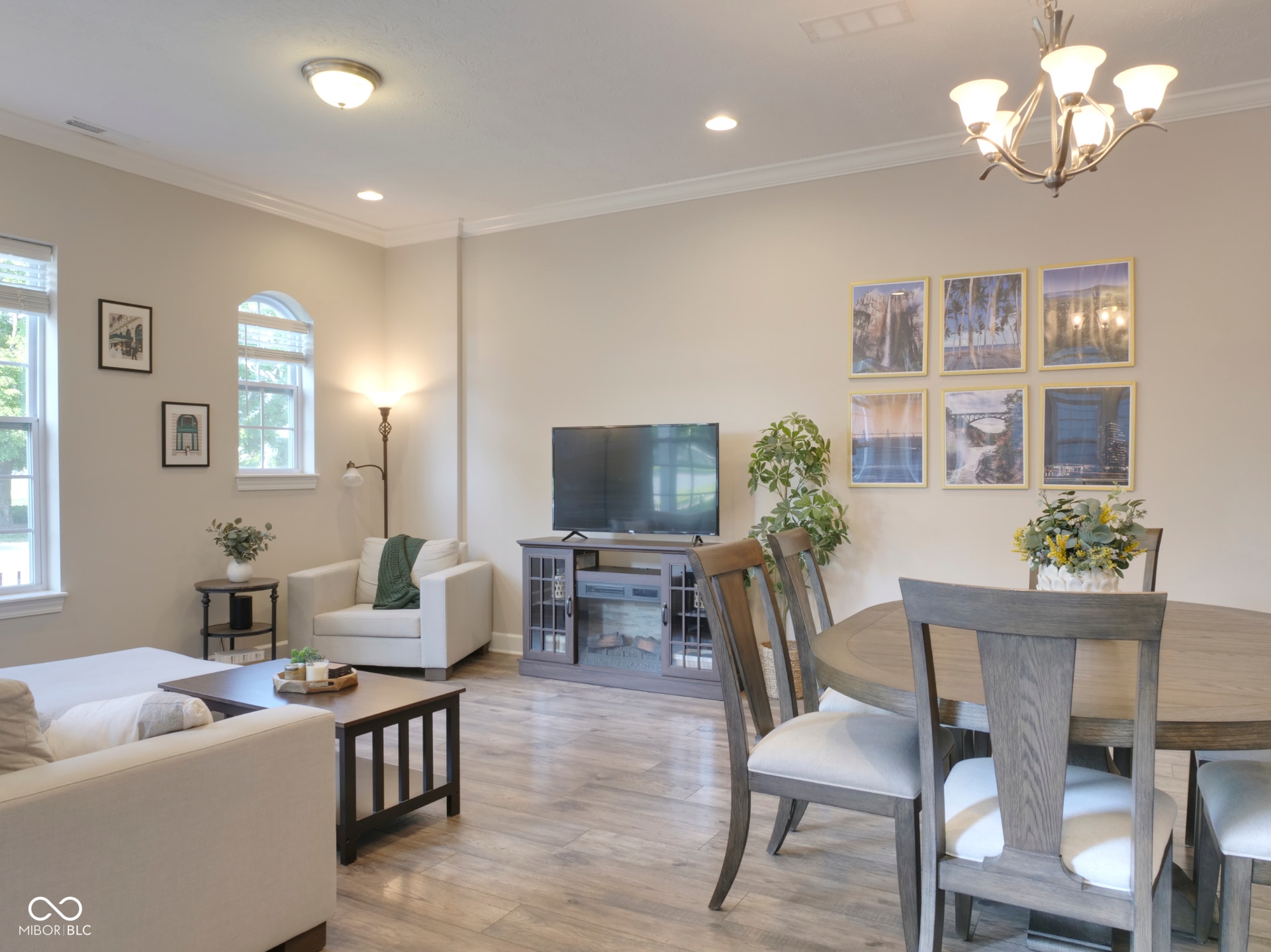 Open-concept living space featuring crown molding, recessed lighting, wood-finish flooring, and an arched window
