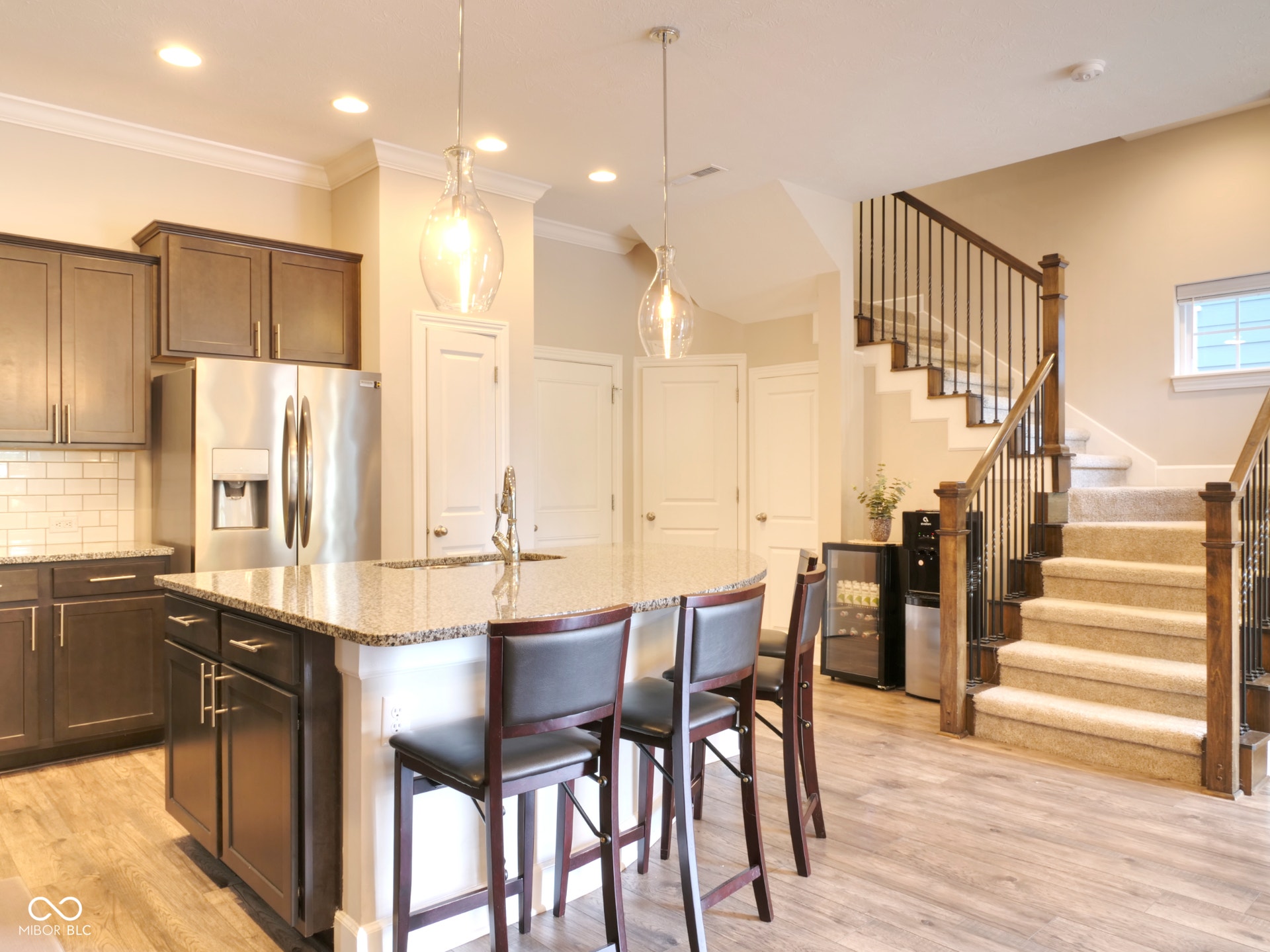 Kitchen featuring an island with stone countertops, dark wood-finish cabinetry, stainless steel appliances, and subway tile backsplash