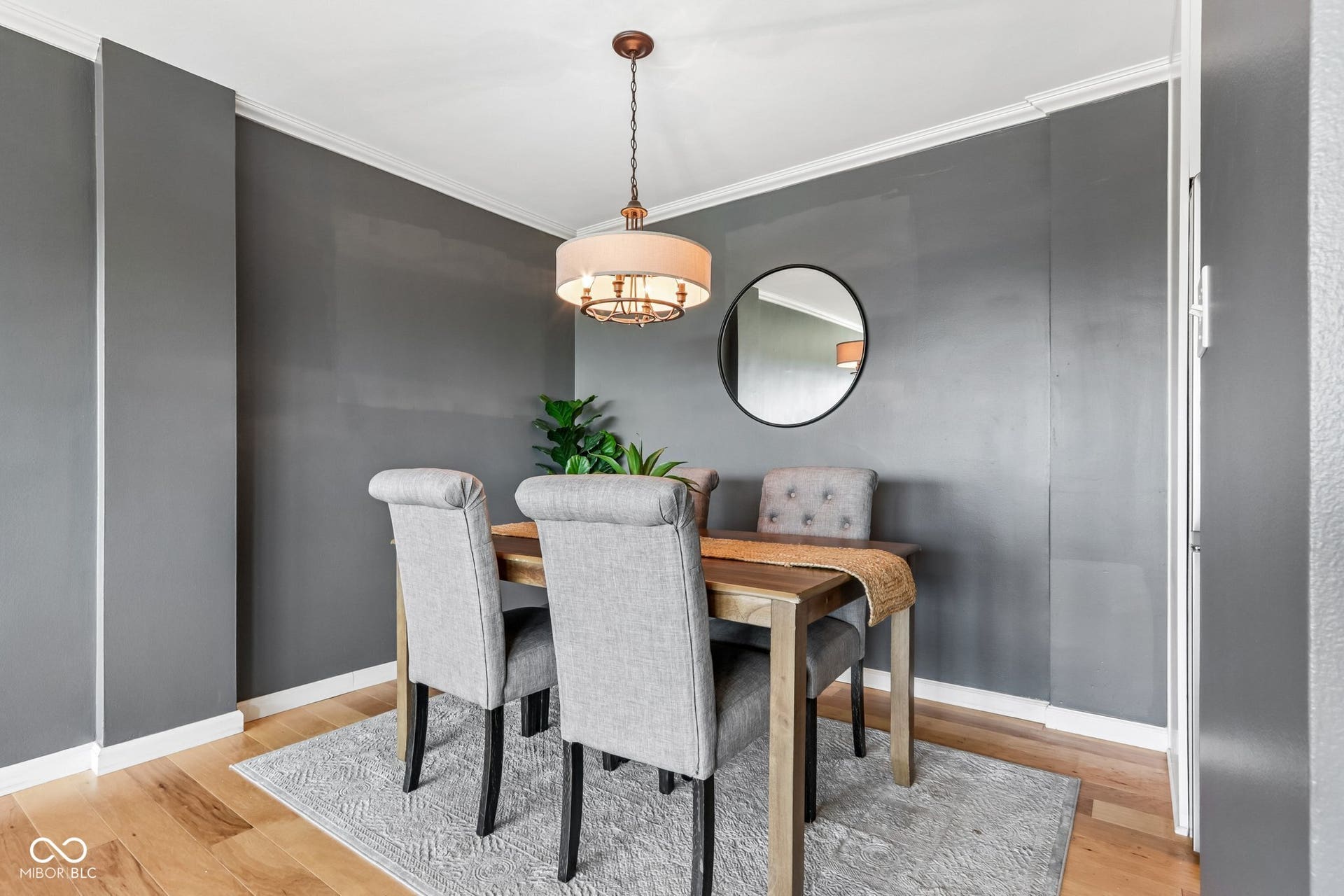 Wood-finish flooring with white baseboards, crown molding, and a pendant light fixture