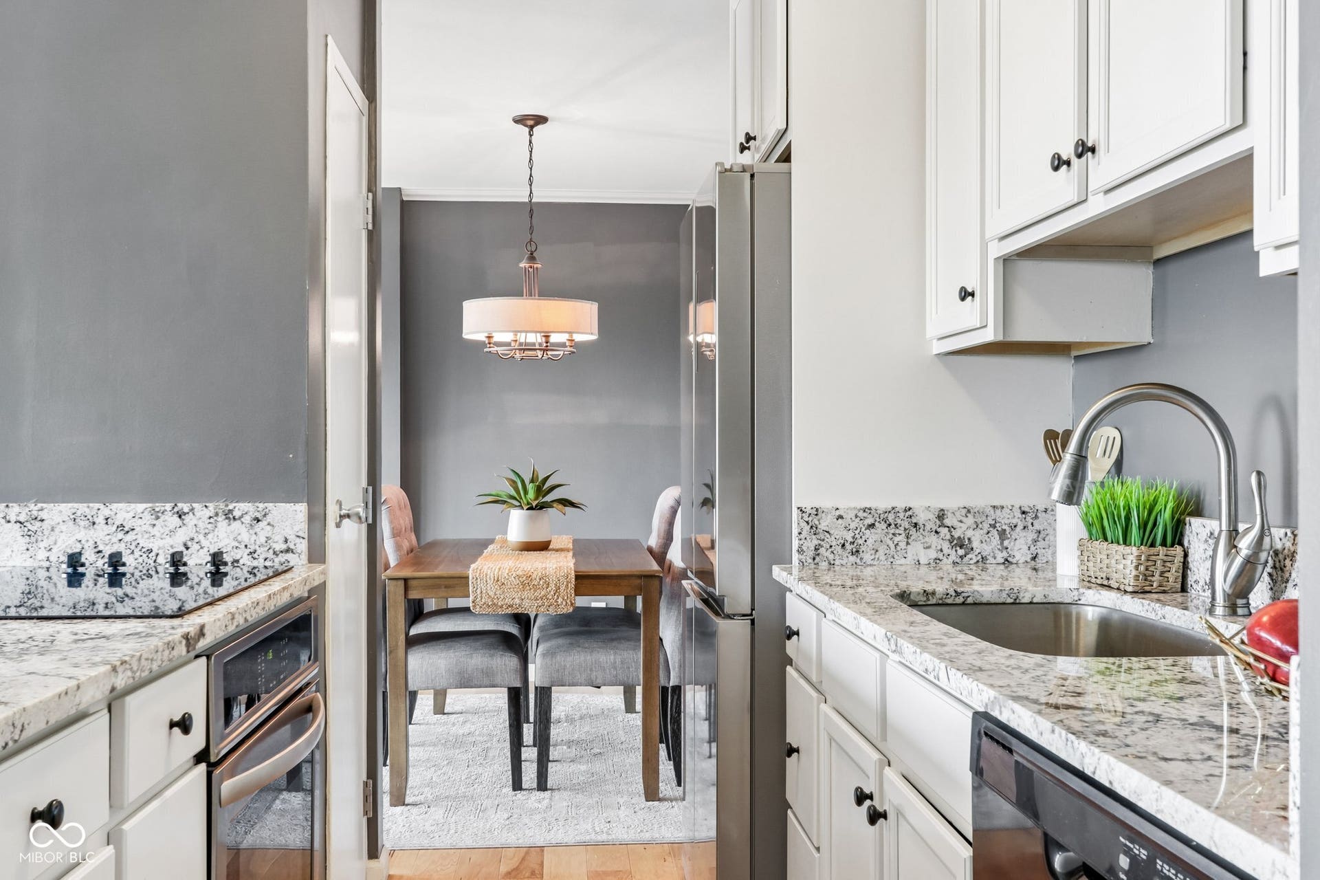 White cabinetry with dark hardware, speckled granite-style countertops, and a stainless steel sink with a gooseneck faucet
