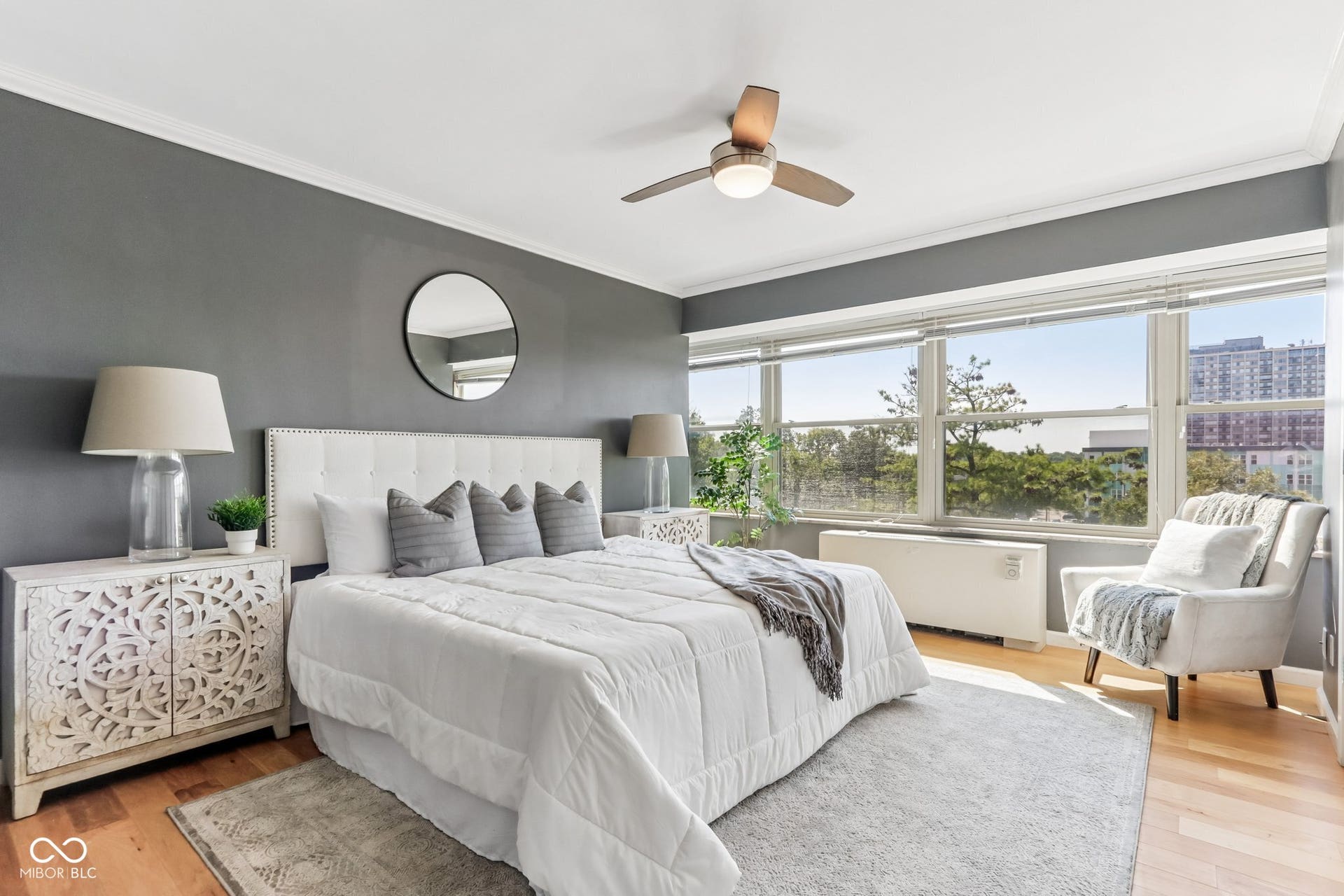 Hardwood flooring, expansive window wall, ceiling fan, crown molding, and a built-in heating unit