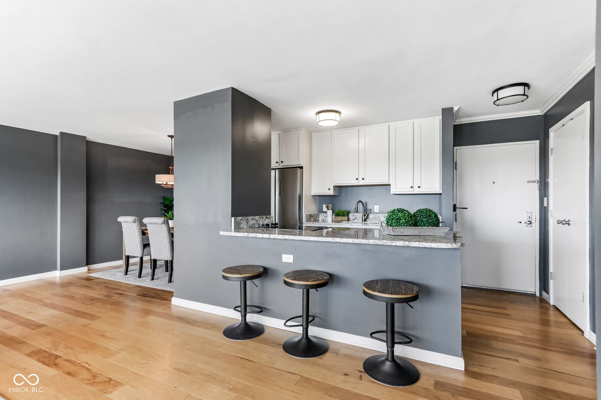 Hardwood flooring, kitchen with white cabinetry, stainless steel appliances, granite countertops, and breakfast bar