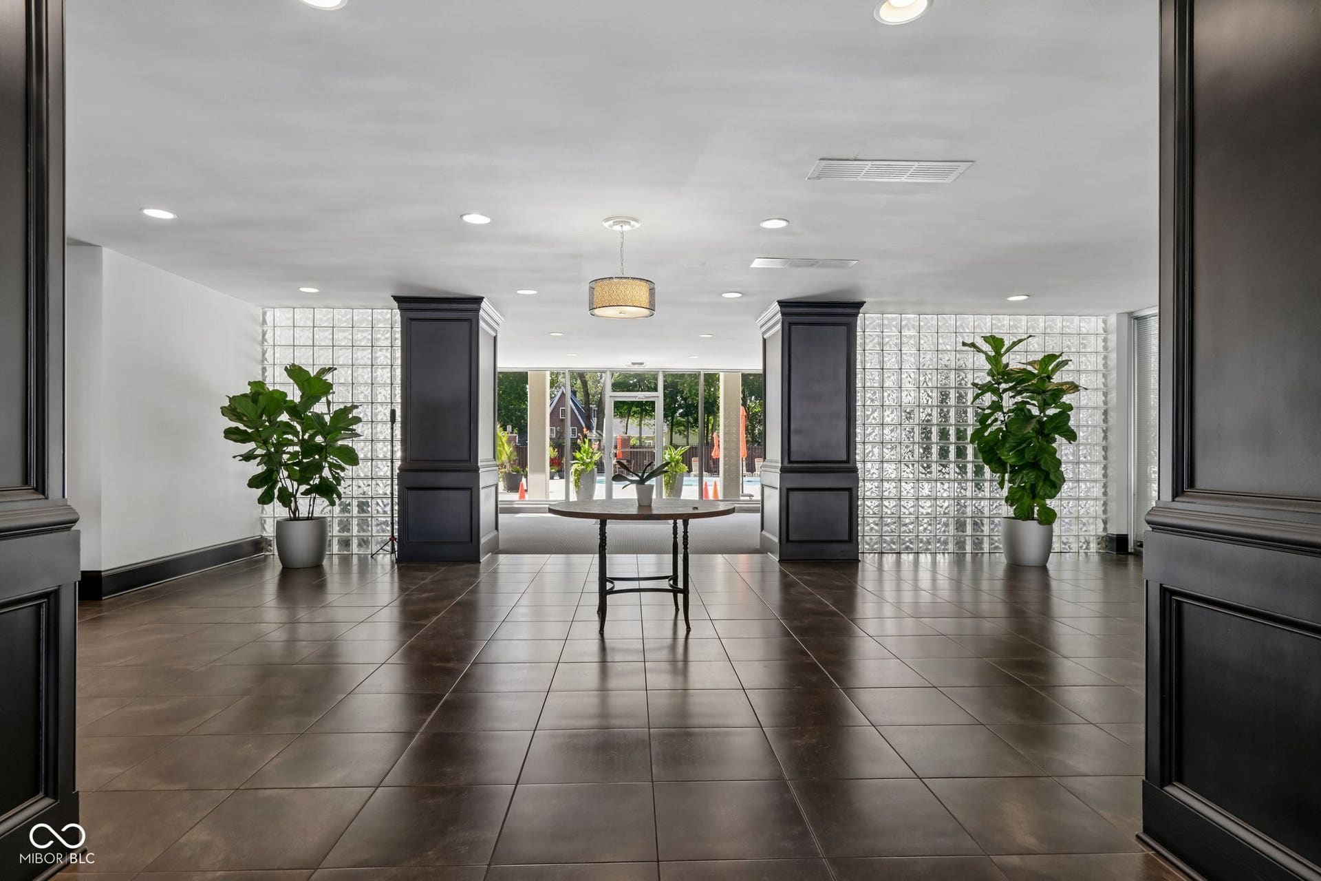 East Building: Spacious entry hall featuring large format floor tiles, recessed lighting, glass block wall elements, and decorative wood paneling