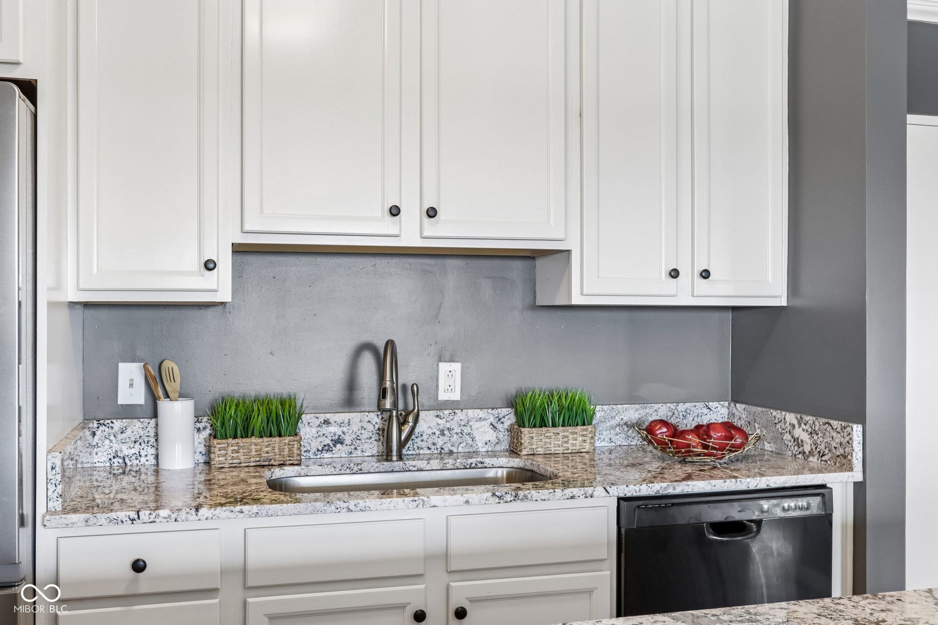 White shaker-style cabinetry with dark hardware, undermount stainless steel sink, granite countertops, and black built-in dishwasher