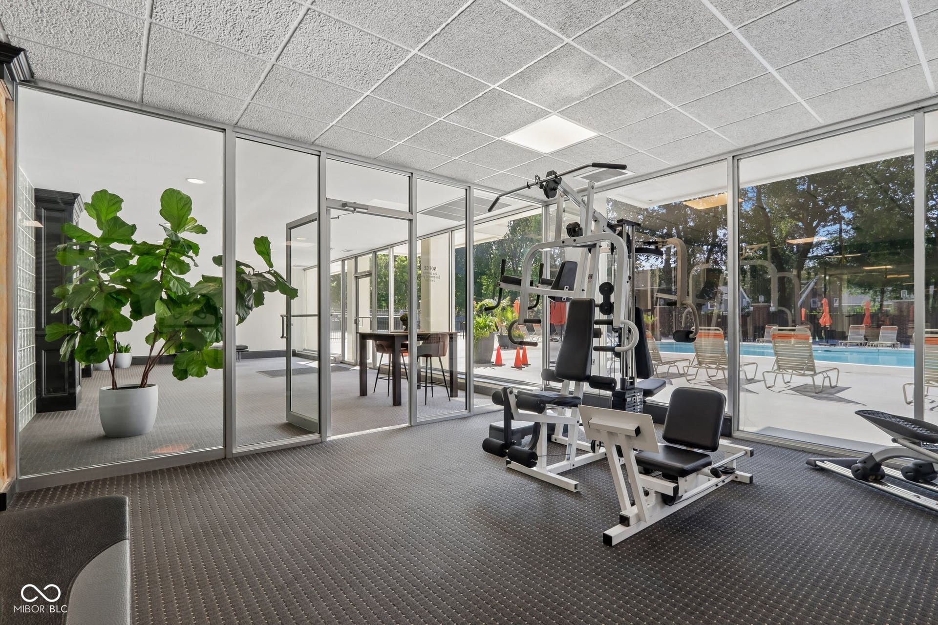 located in the East Building: Fitness room with floor-to-ceiling glass paneling, direct pool access, and resilient rubberized flooring