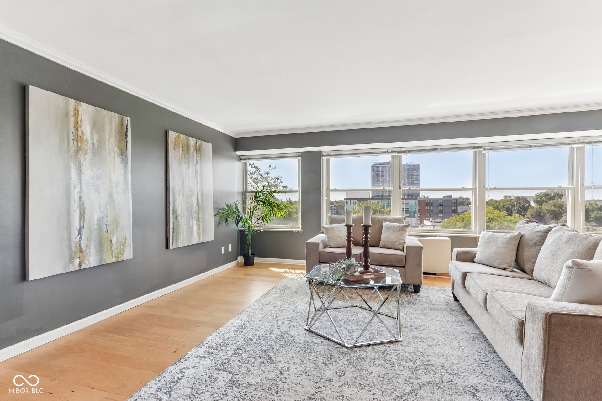 Bright living area featuring expansive windows, light wood-finish flooring, and crown molding