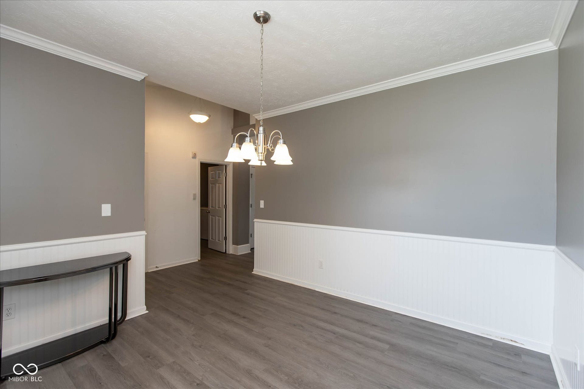 Spacious interior featuring wood-finish flooring, white beadboard wainscoting, and crown molding