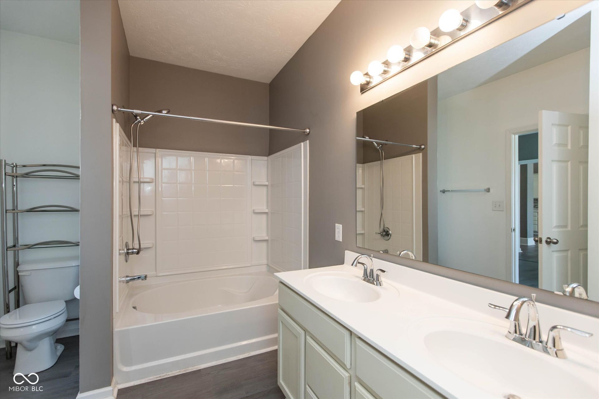 Bathroom featuring a dual vanity with integrated sinks, chrome faucets, and a large wall-mounted mirror