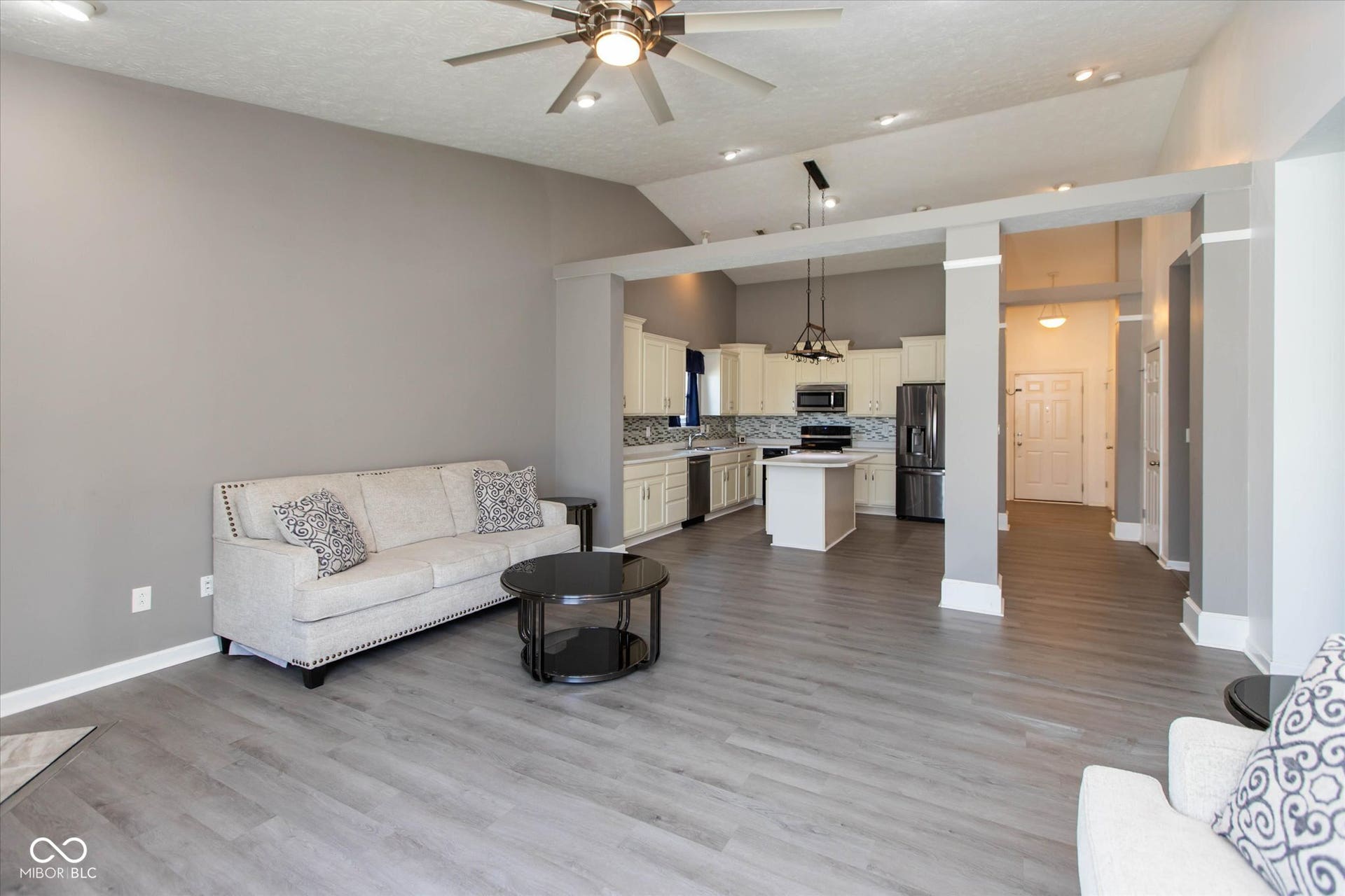 Open-concept living space featuring wood-finish flooring, vaulted ceilings, and recessed lighting