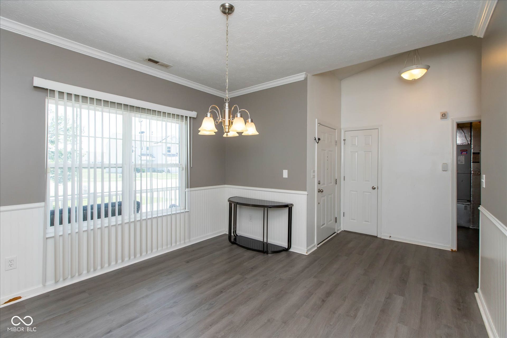 Dining area featuring wood-finish flooring, wainscoting, and crown molding