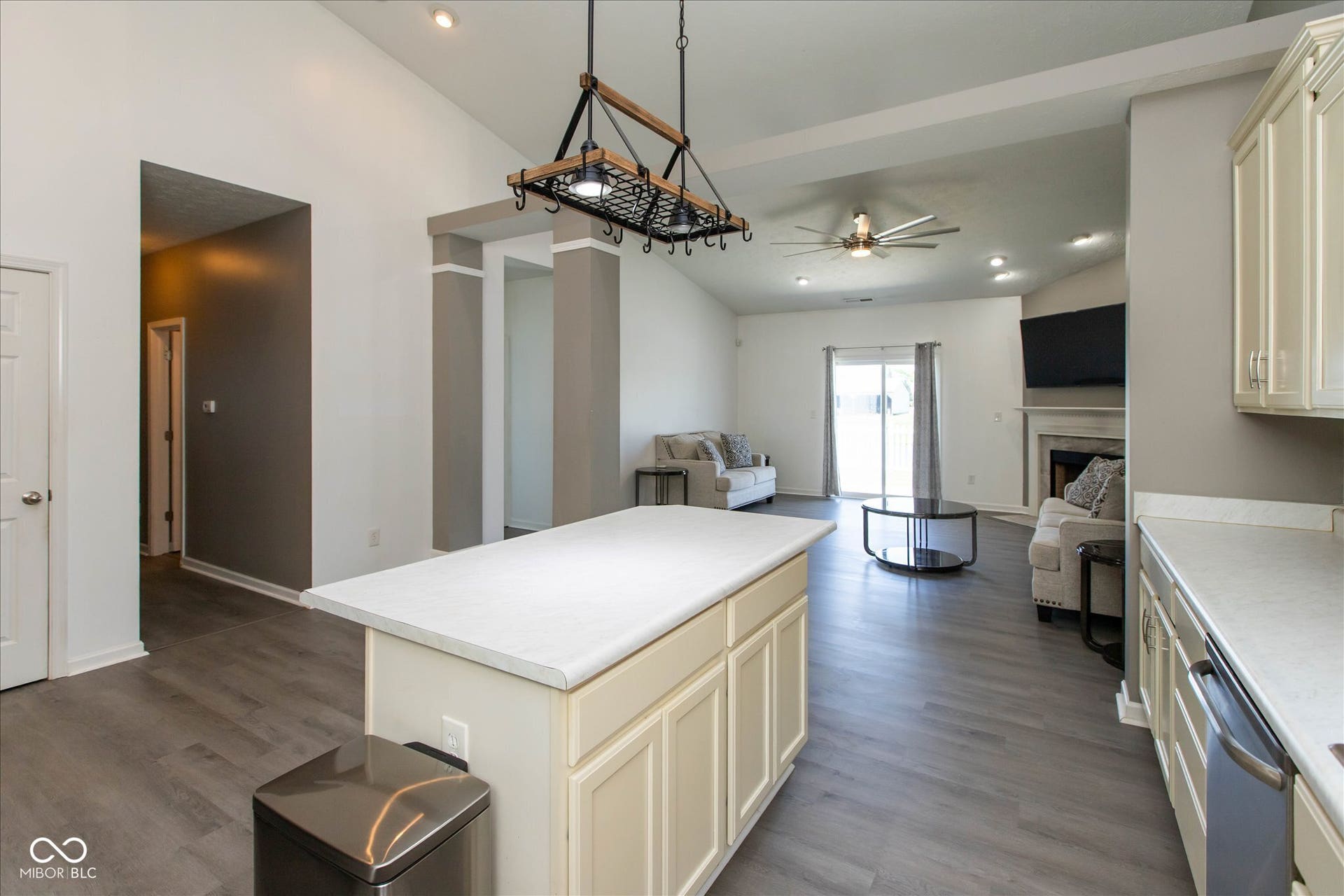 Kitchen island with a light-toned countertop and cabinetry, wood-finish flooring, vaulted ceilings, recessed lighting, and a pot rack light fixture