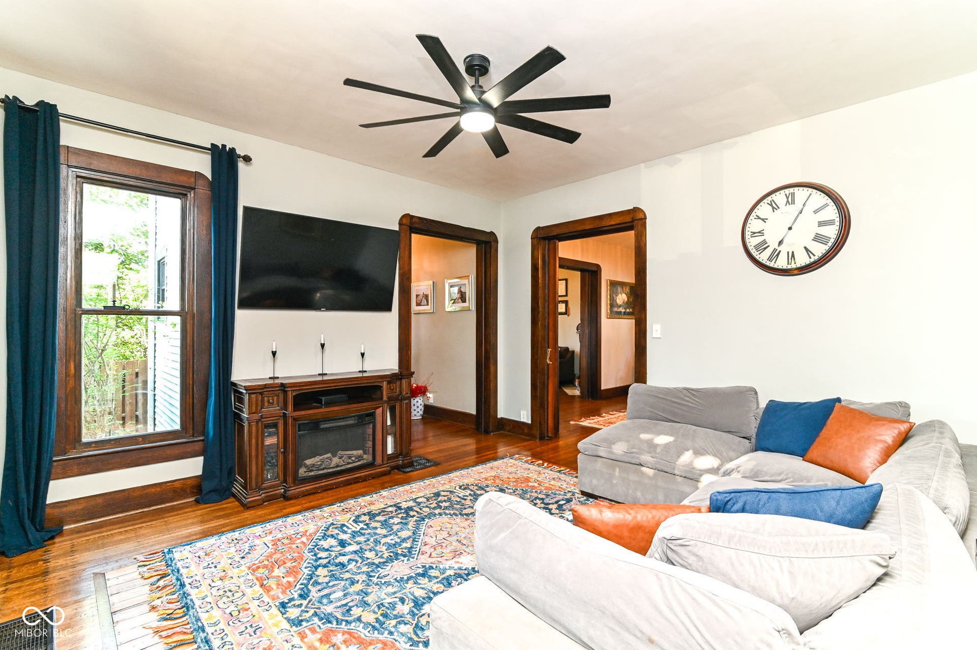 Spacious main-level living room with restored hardwood floors, tall windows, ceiling fan and easy flow to the dining room.