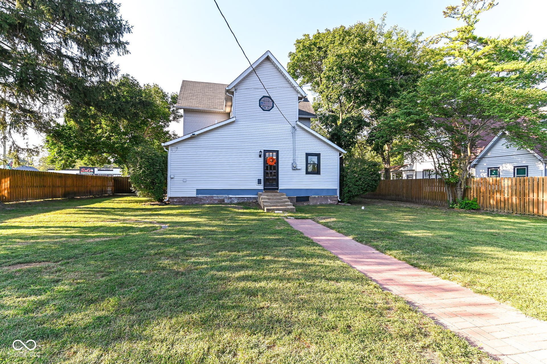 Rear view highlights the home's historic architecture, fenced backyard and convenient path to the detached garage.