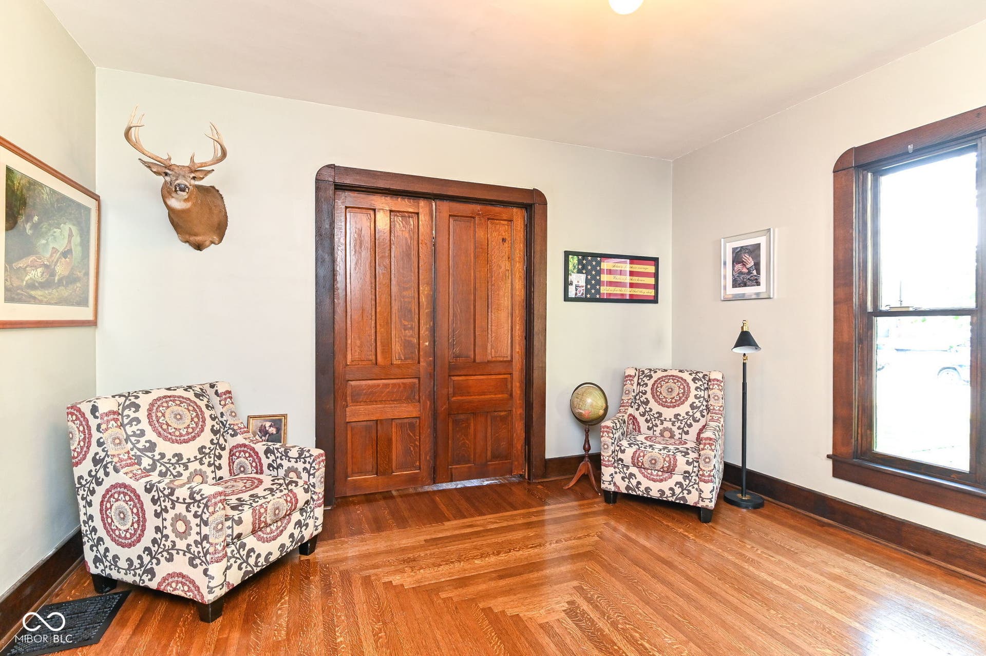 Front sitting room showcases restored quarter-sawn white oak floors, original double pocket doors, tall windows and rich historic millwork.