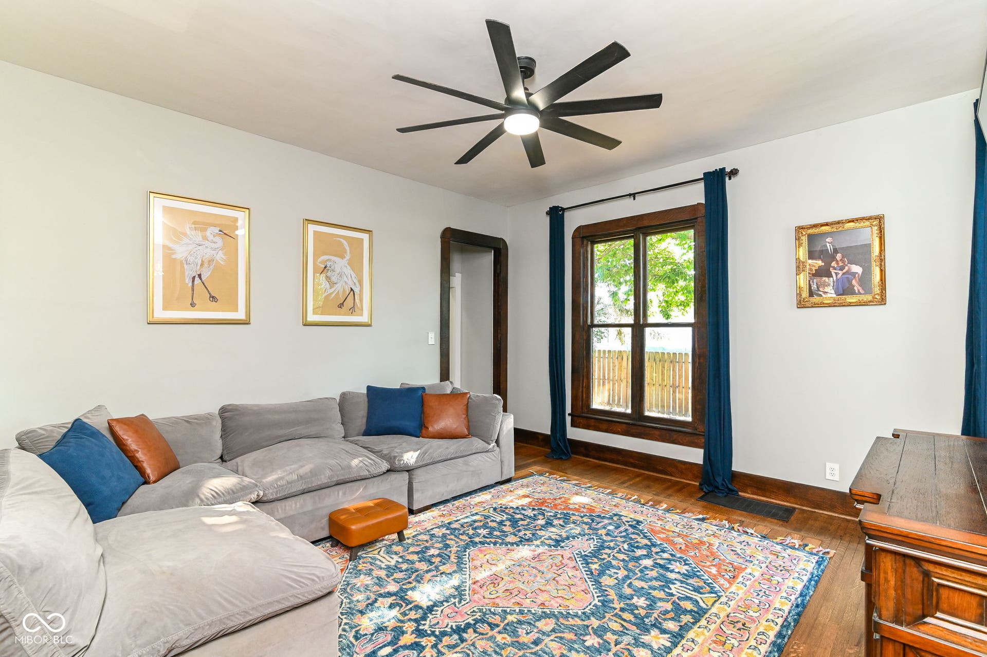 Bright living room with large windows, warm wood floors and generous space for everyday living or entertaining.