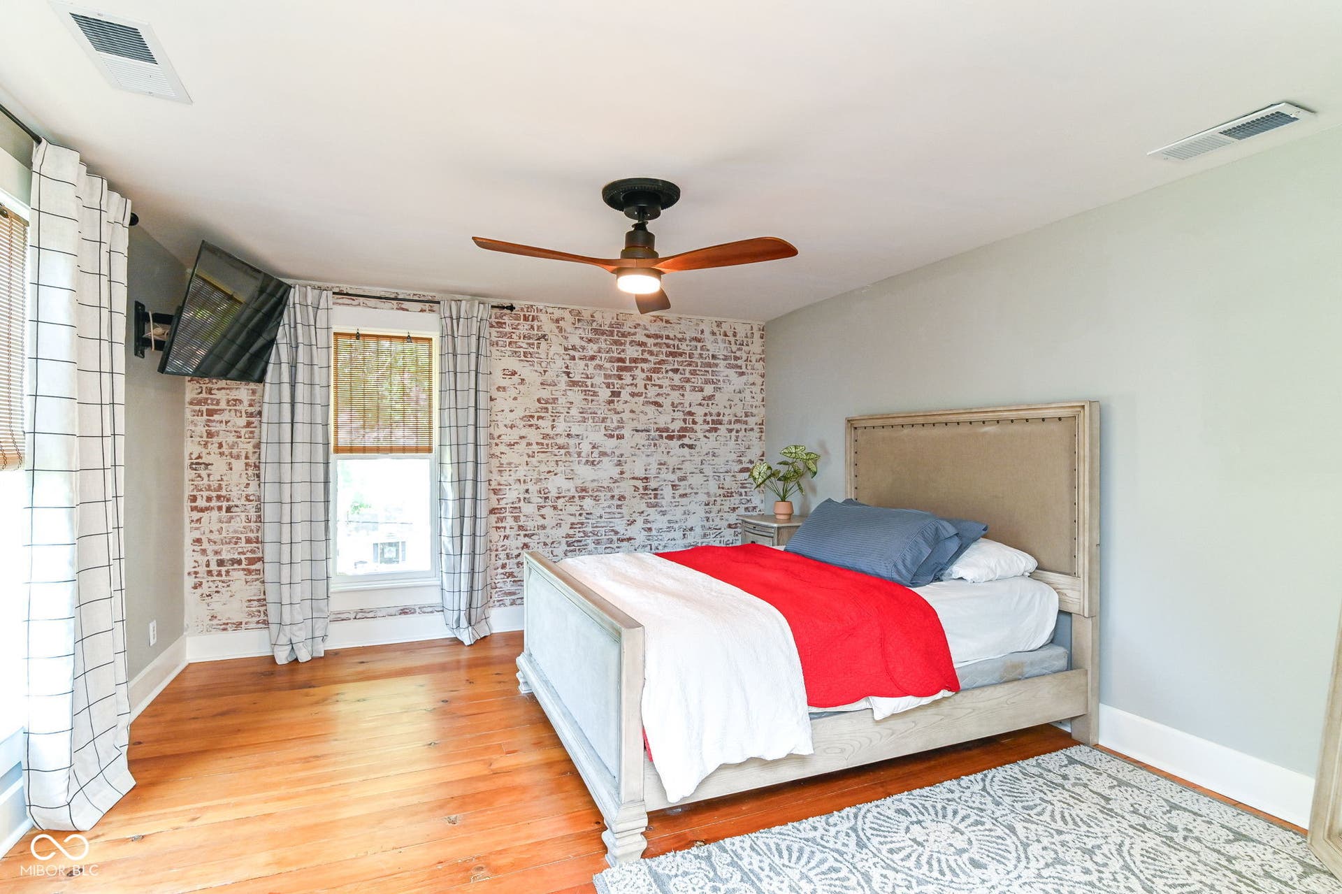 Another spacious bedroom view highlights original pine floors, tall windows and abundant natural light.