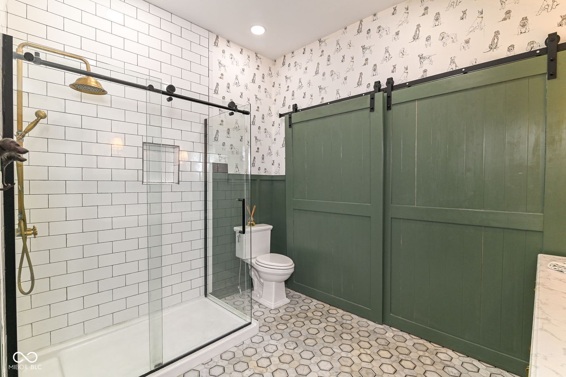 Main-level full bath blends vintage-inspired style with modern luxury, including heated marble flooring, tiled walk-in shower and bold barn-style doors.