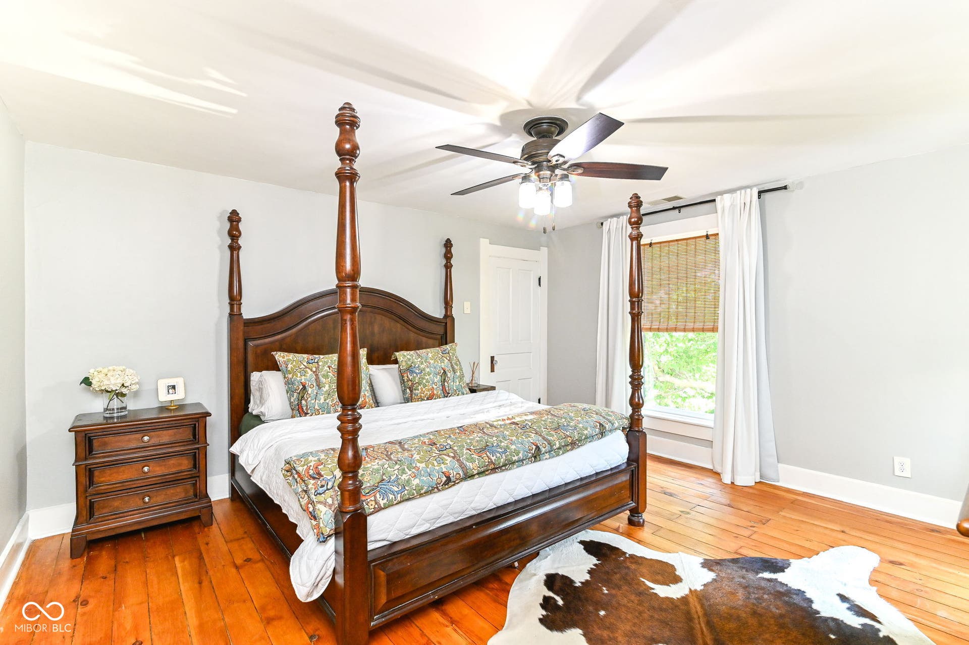 Large bedroom with original pine floors, multiple windows, ceiling fan and plenty of room for a king-size bed.