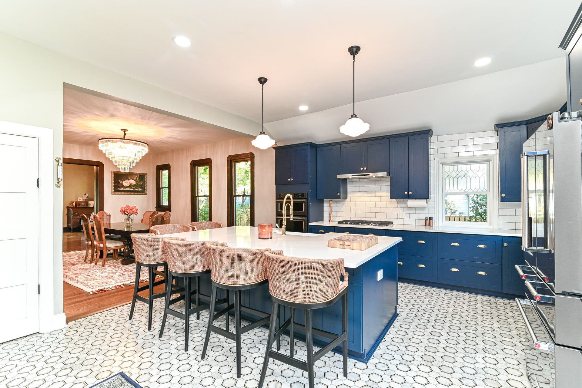 Open kitchen and dining layout features a substantial island, gas cooktop, statement lighting, quartz countertops and heated marble floors.
