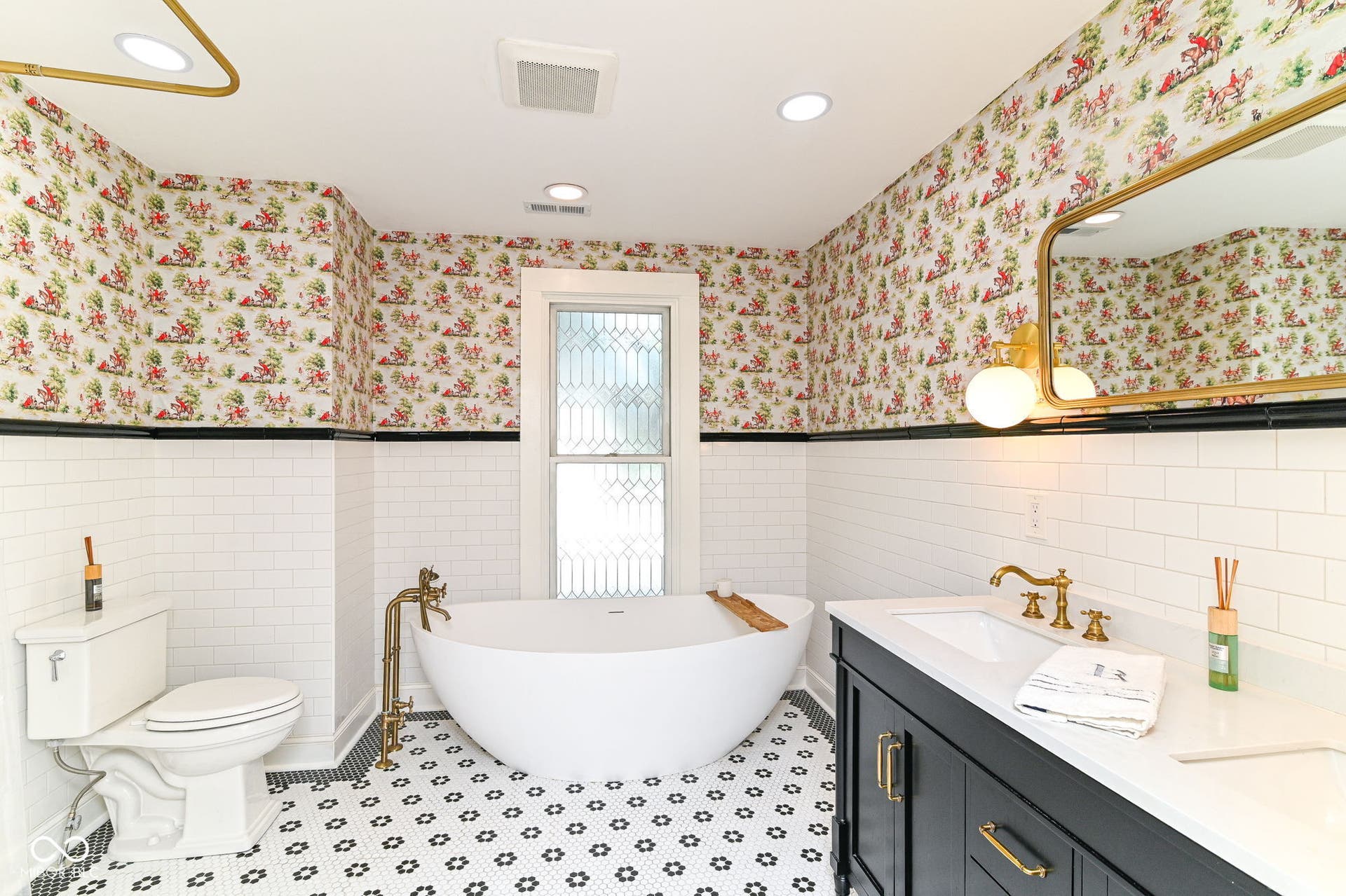 Upstairs full bath feels like a retreat with solid-stone soaking tub, double vanity, marble details and brass-toned fixtures.