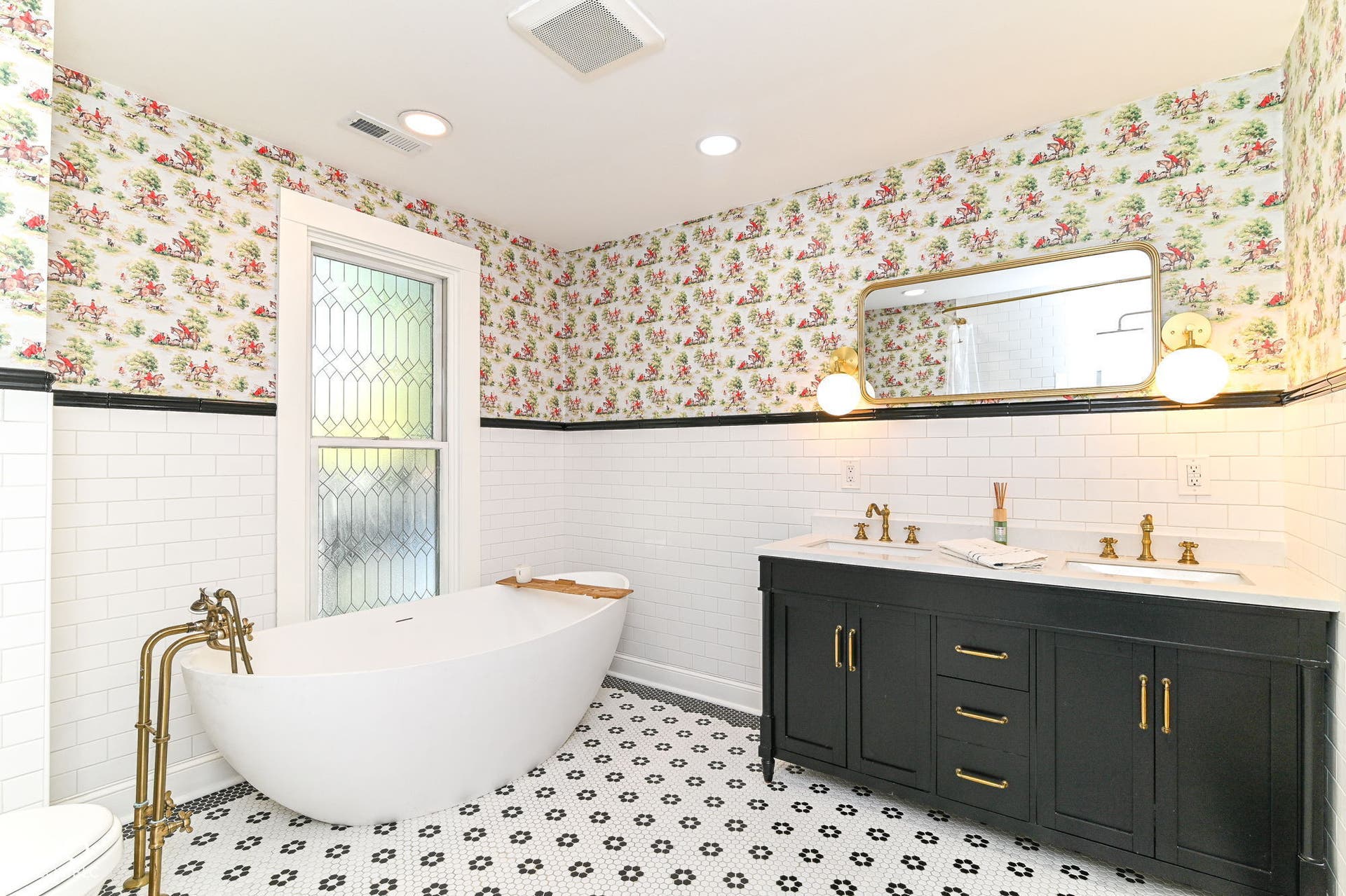 Double vanity, soaking tub and elegant brass-toned fixtures create a beautifully updated bath with vintage-inspired character.