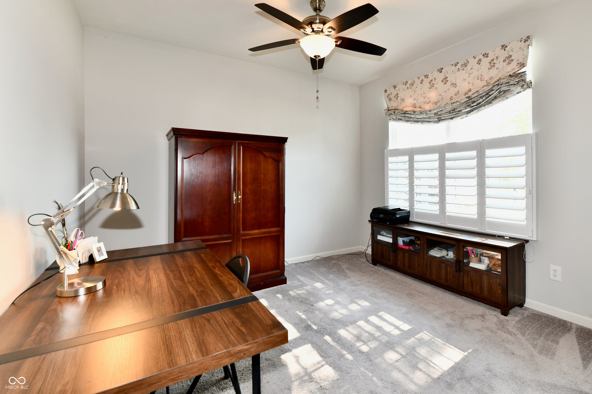 White walls, light gray carpeting, and a ceiling fan with integrated lighting