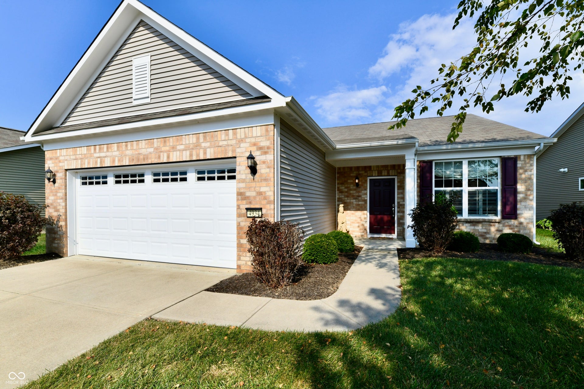 Brick and siding exterior with an attached garage, covered entryway, and a concrete walkway