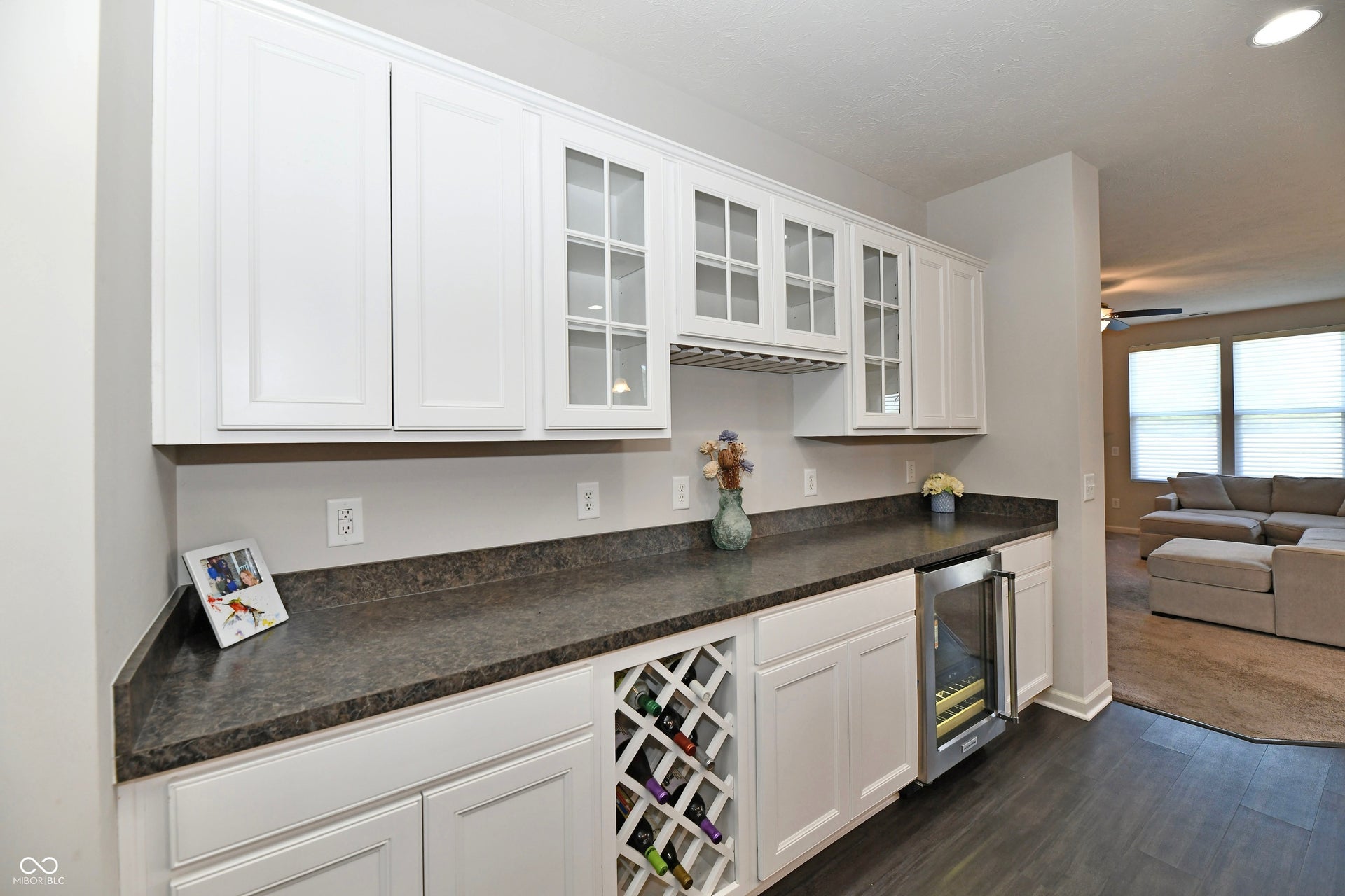 Built-in cabinetry with a beverage refrigerator, a wine rack, overhead storage, and glass-front upper cabinets