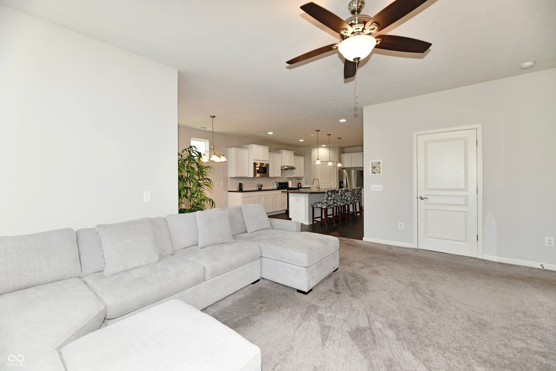 Open-concept living space featuring a ceiling fan with light fixture, light gray walls