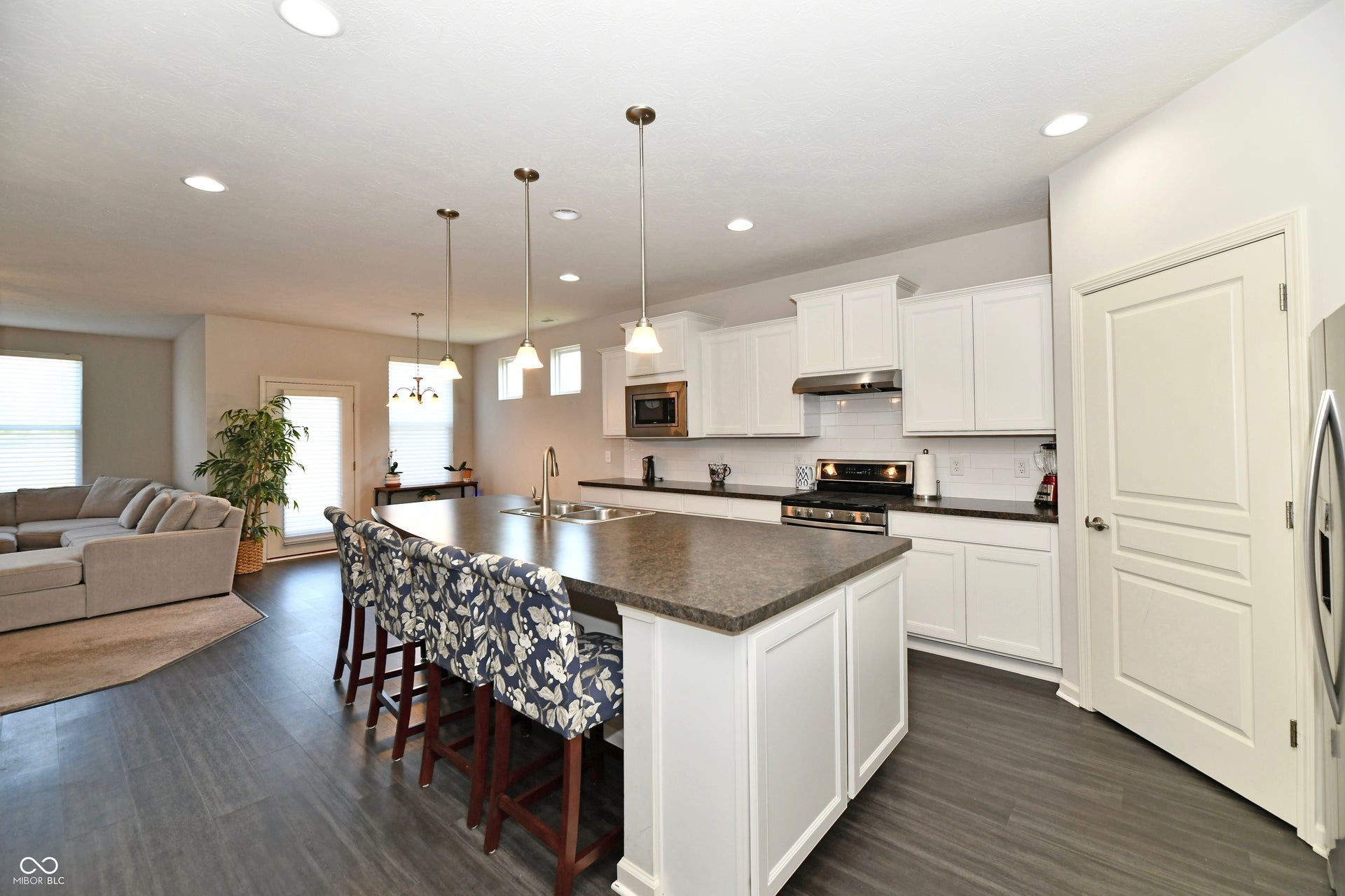 Kitchen featuring an island with seating, white cabinetry, dark countertops, and stainless steel appliances